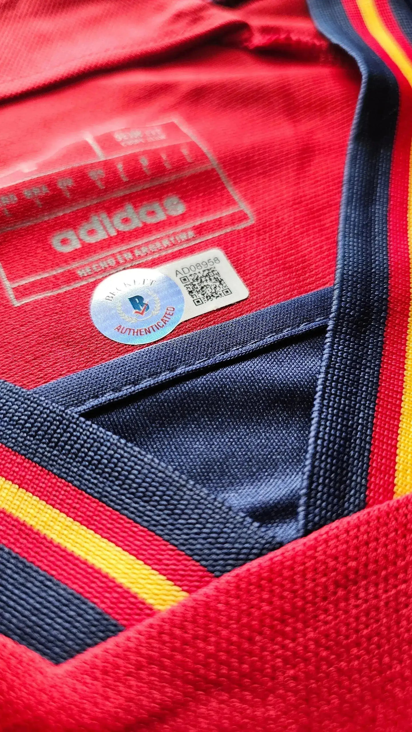 Inside view showing adidas label and authenticity sticker on a red Spain soccer jersey.