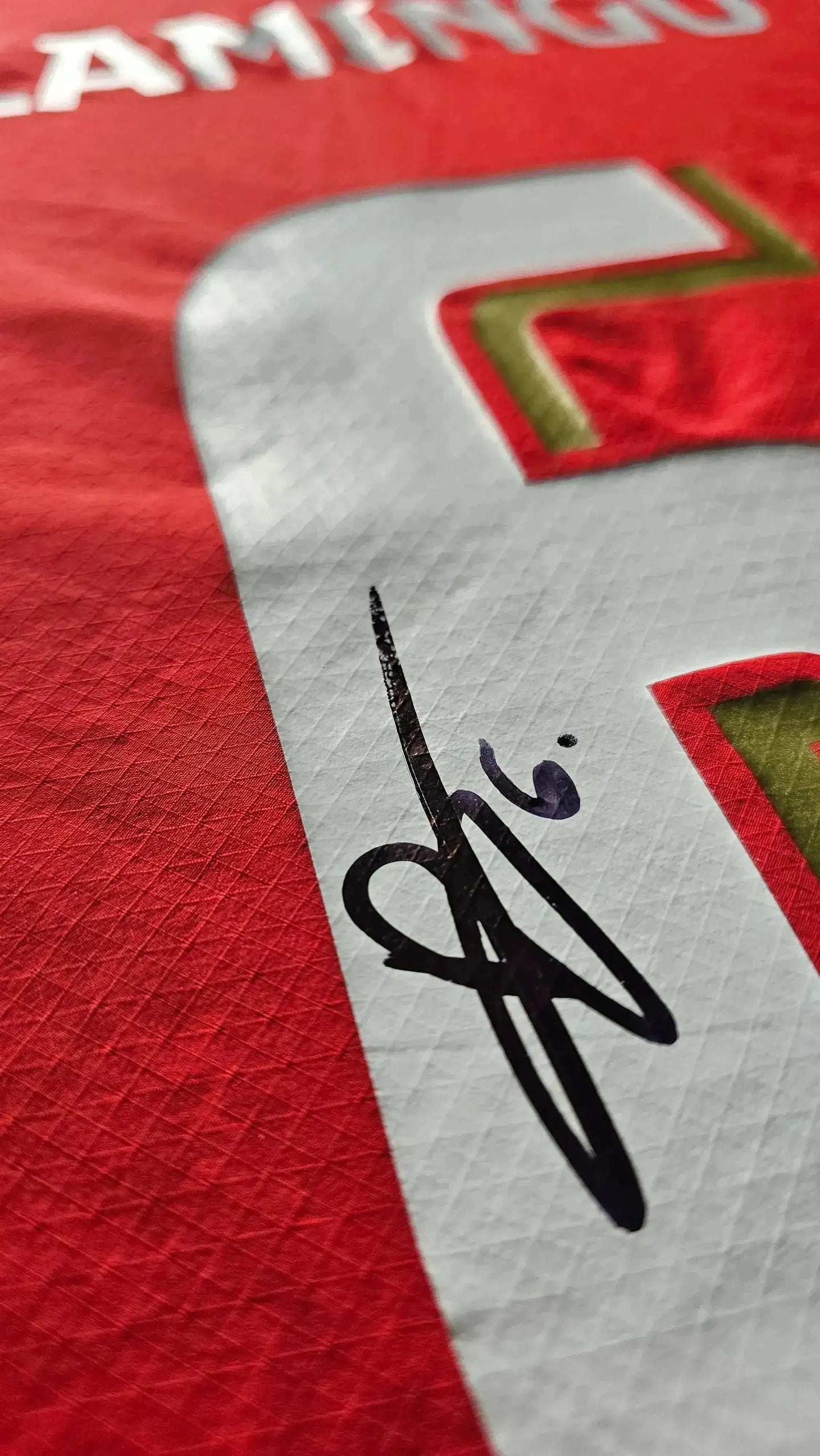 Detail showing the signature of Ryan Flamingo on a red PSV Eindhoven football shirt.