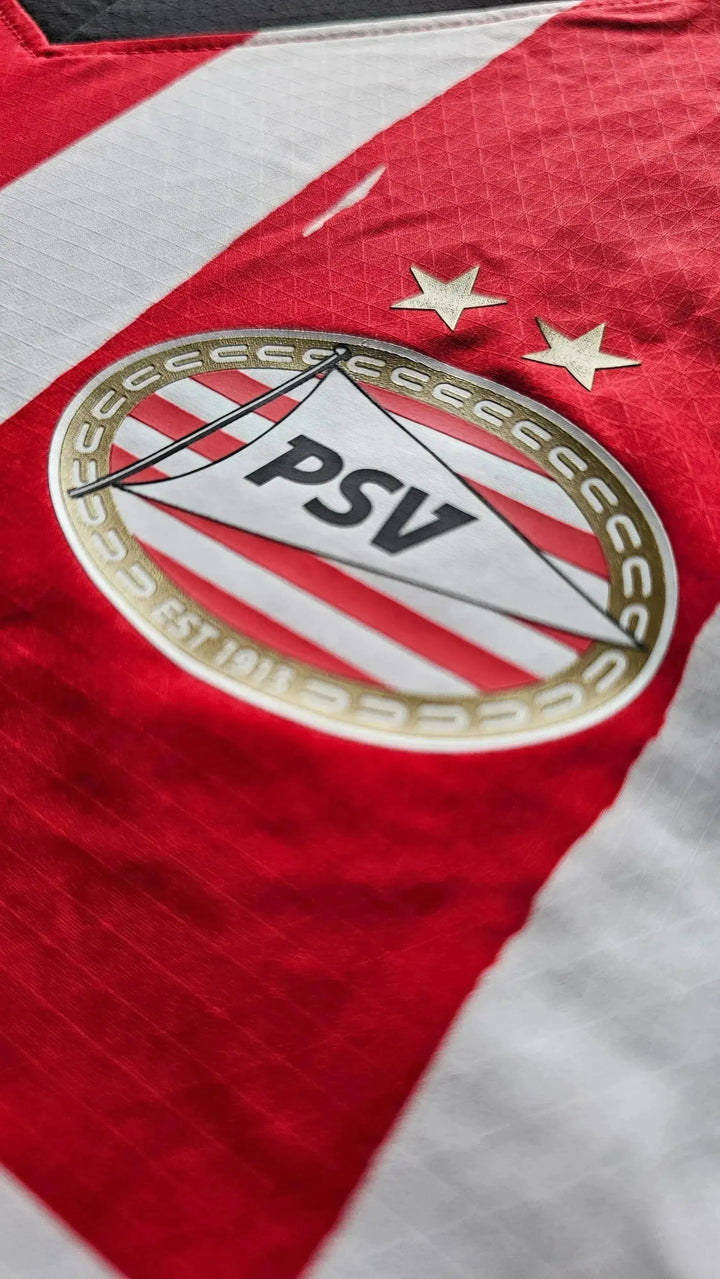PSV Eindhoven crest with two stars on a red and white striped background.