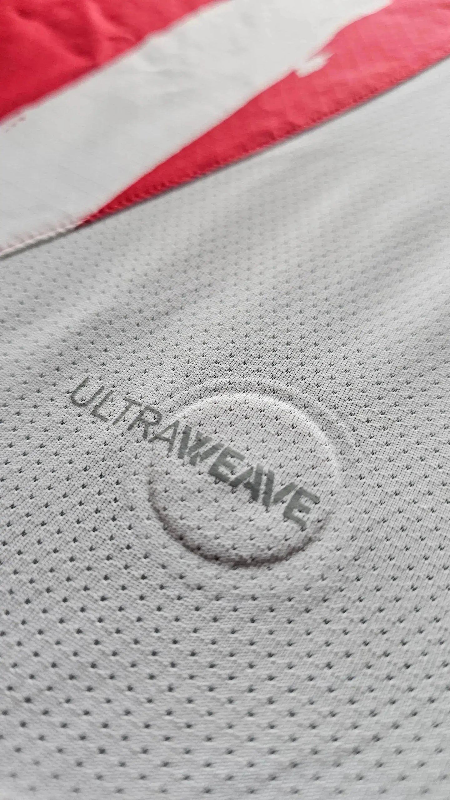 Close-up detail featuring the ULTRAWEAVE texture on the red and white PSV signed football shirt.
