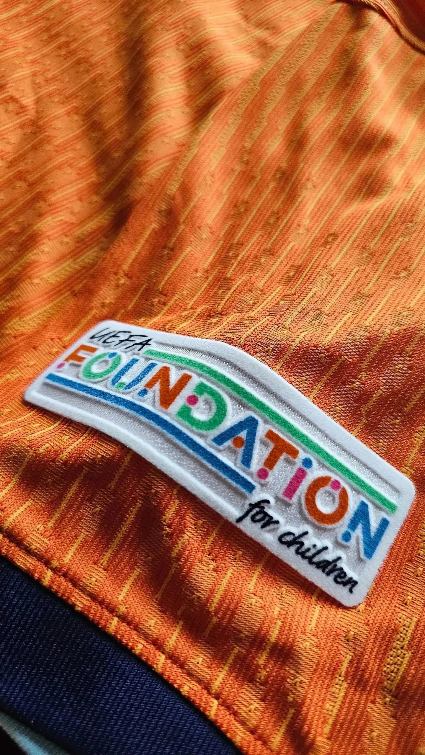 Close-up of the UEFA Foundation for children logo on the orange football shirt.