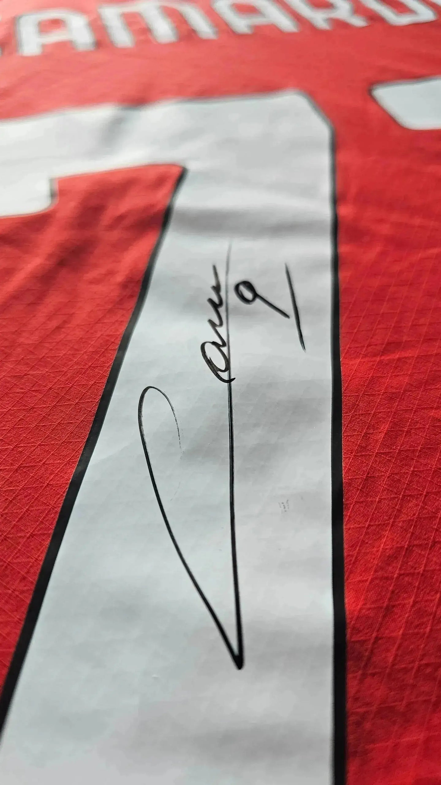 Detail showing signature of Camarda on a red football shirt with No. 9.