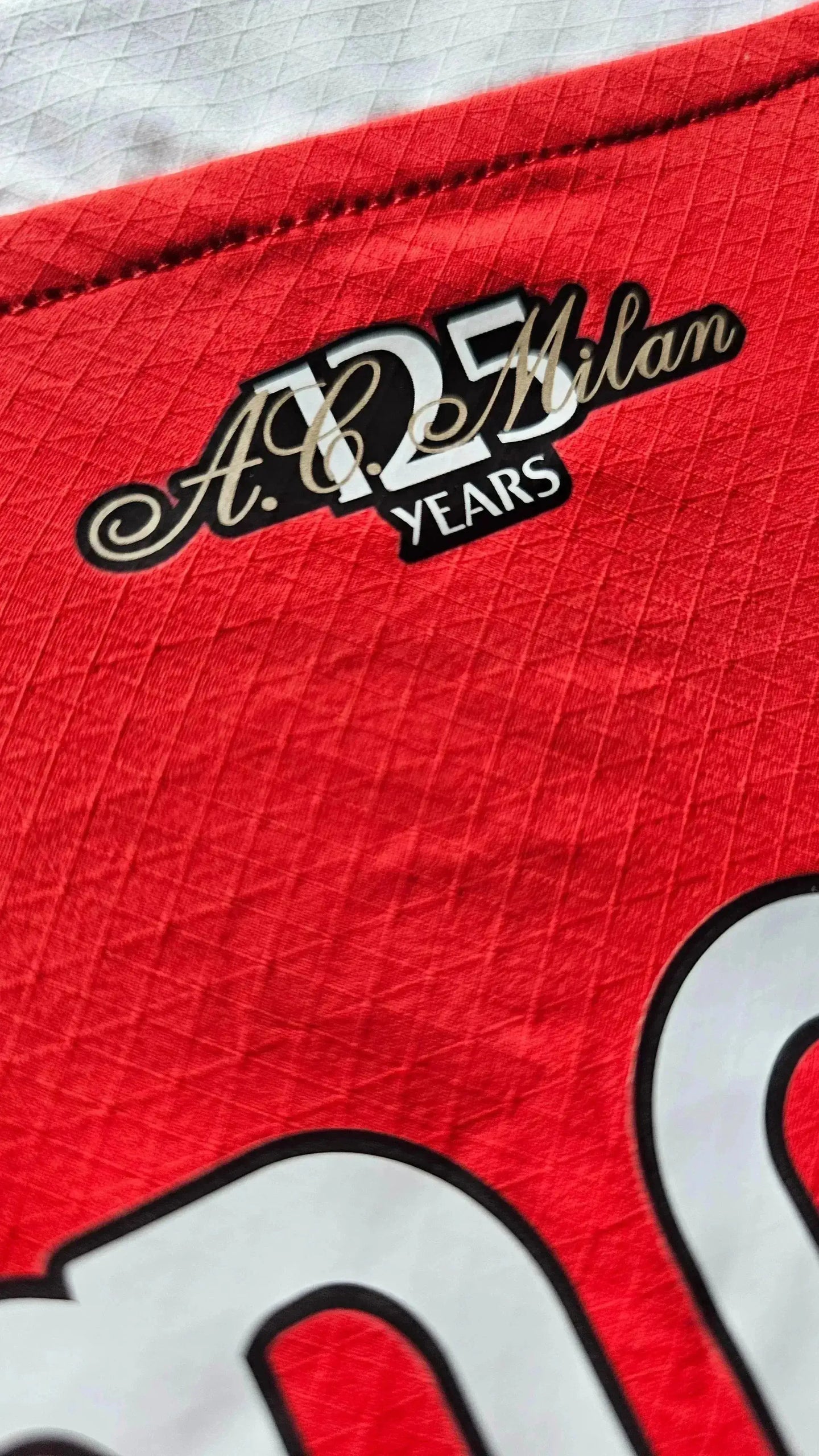 AC Milan 125 Years emblem featuring red and black stripes with decorative text detail.