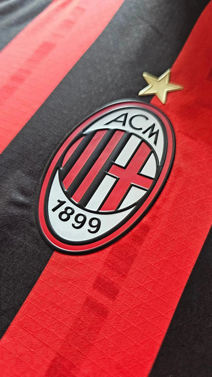Close-up of AC Milan crest featuring black and red stripes and a gold star above 1899.