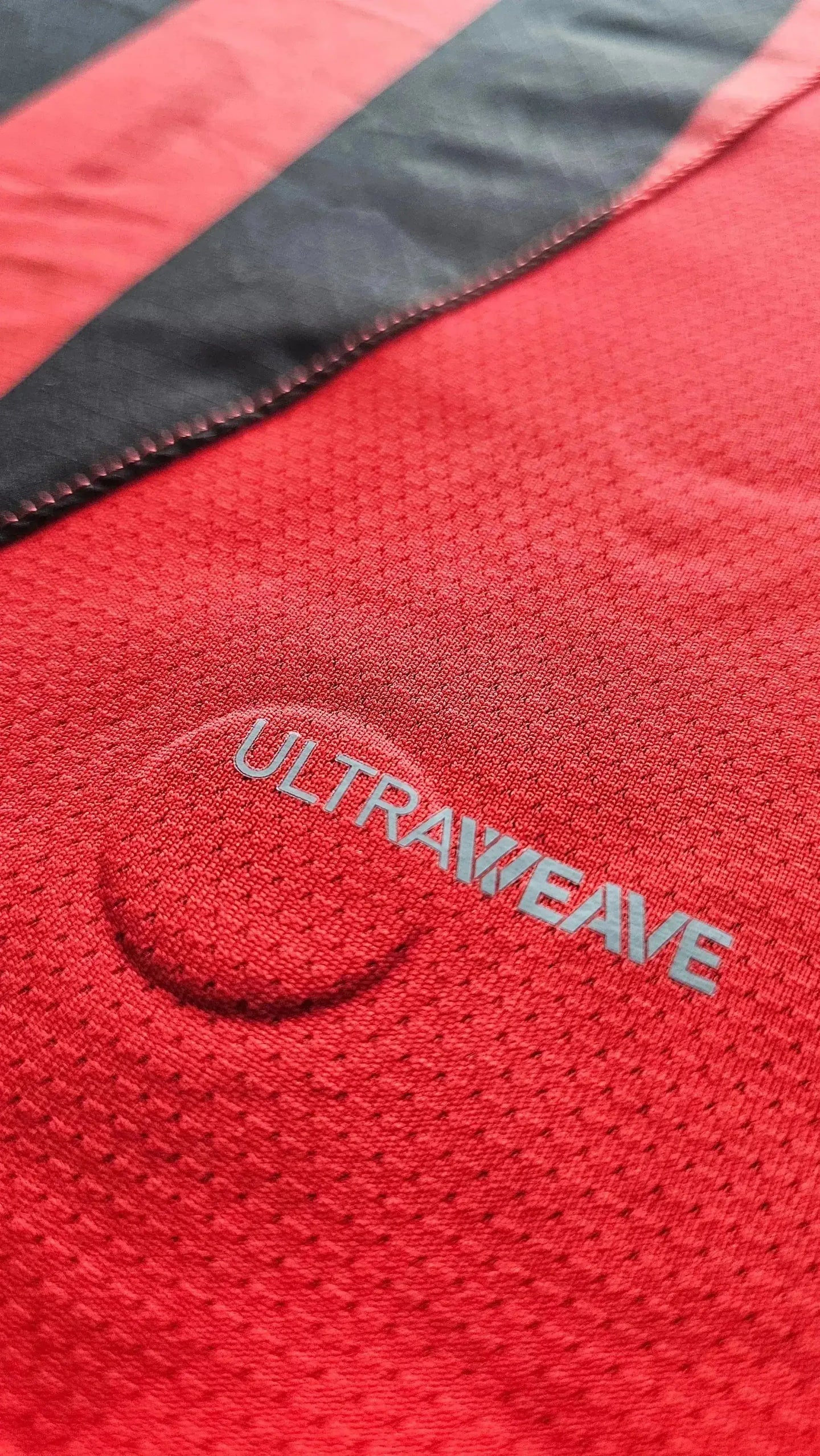 Detail of AC Milan football shirt showing red and black stripes with "ULTRAWEAVE" text.