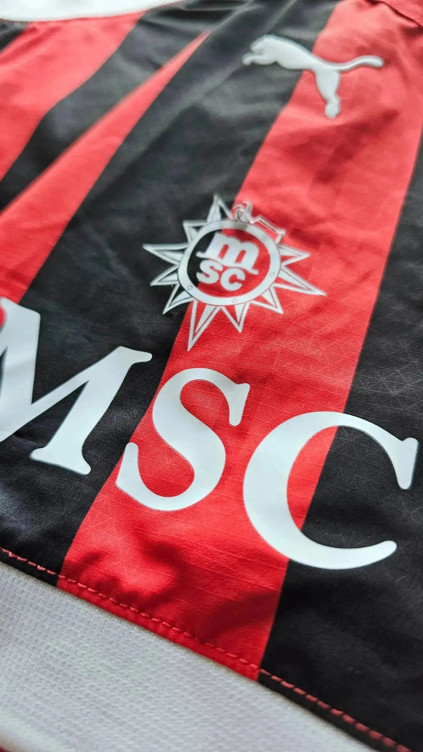Close-up of AC Milan signature detail with crest featuring 'msc' and red stripes.