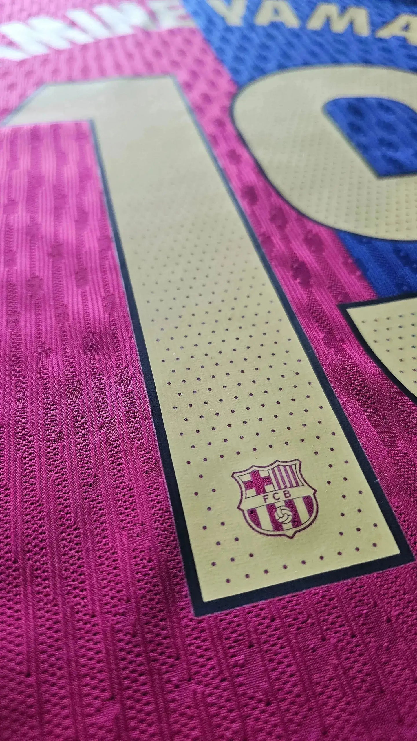 Detail view of Lamine Yamal 19 on pink and blue football shirt with FCB crest.