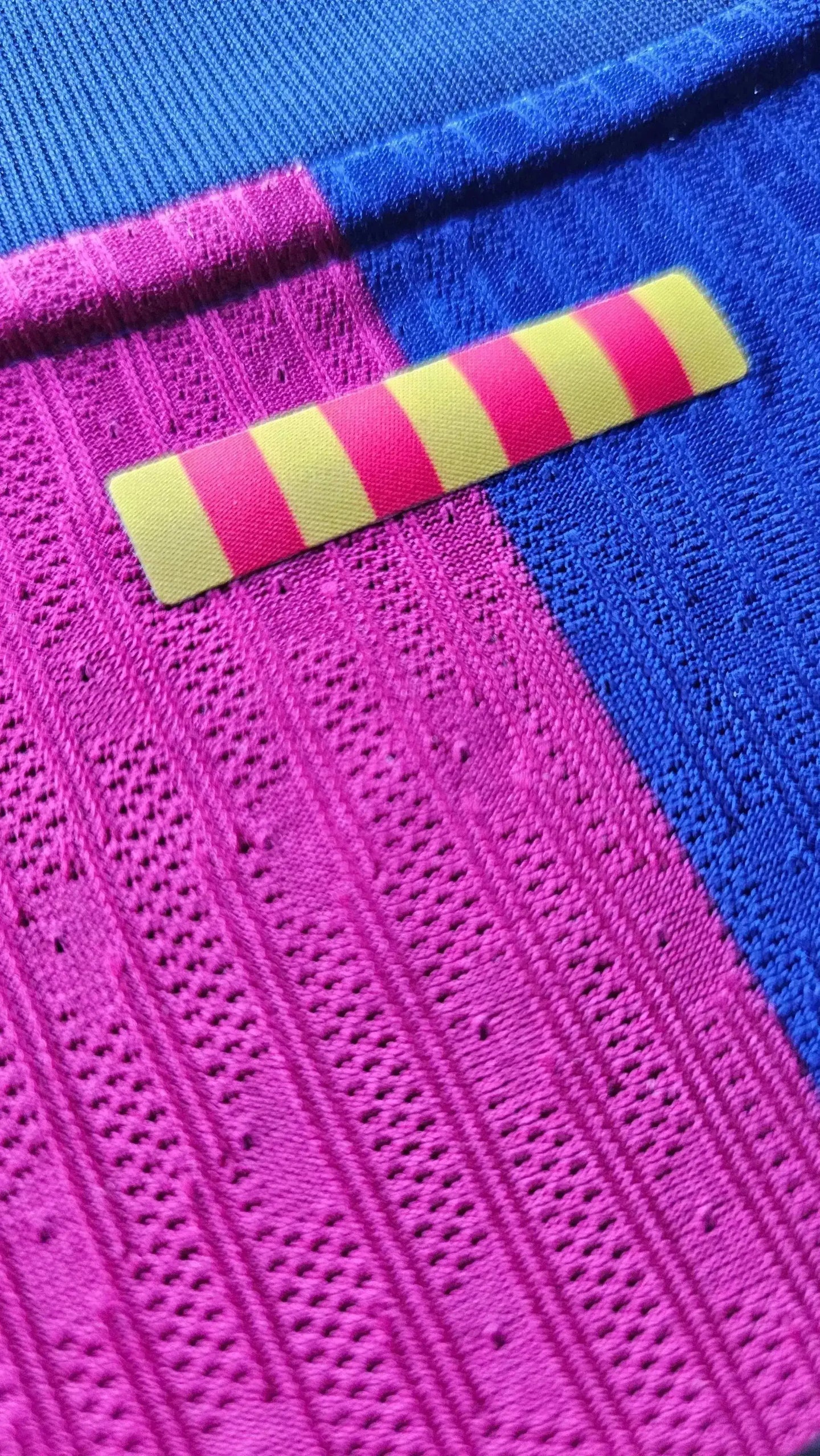 Detail showing the pink and blue fabric pattern with a yellow and red striped label.