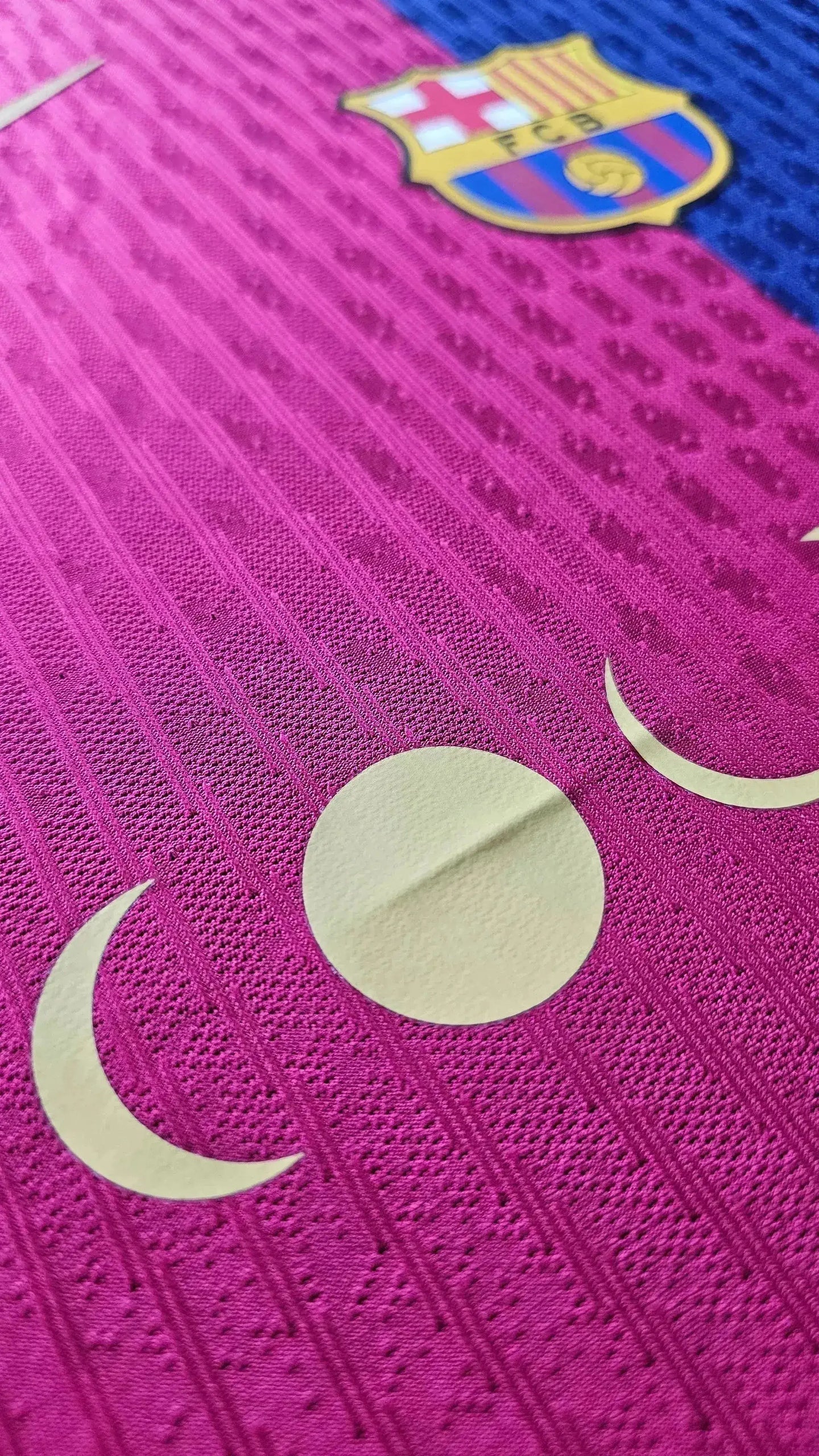 Crest detail of FC Barcelona, featuring the iconic crest and a textured pink background.