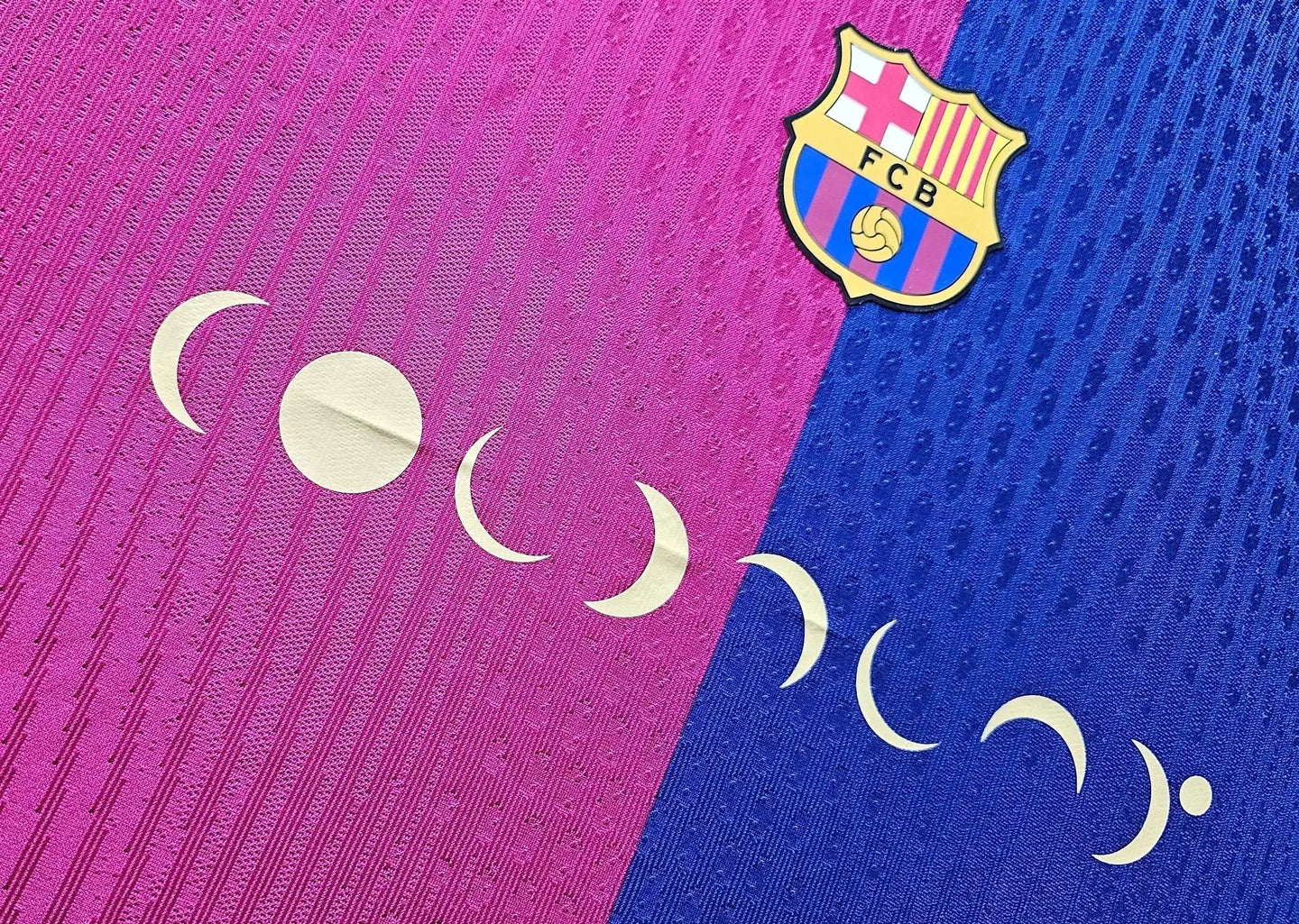 Detail showing FC Barcelona crest and white crescent patterns on a pink and blue football shirt.