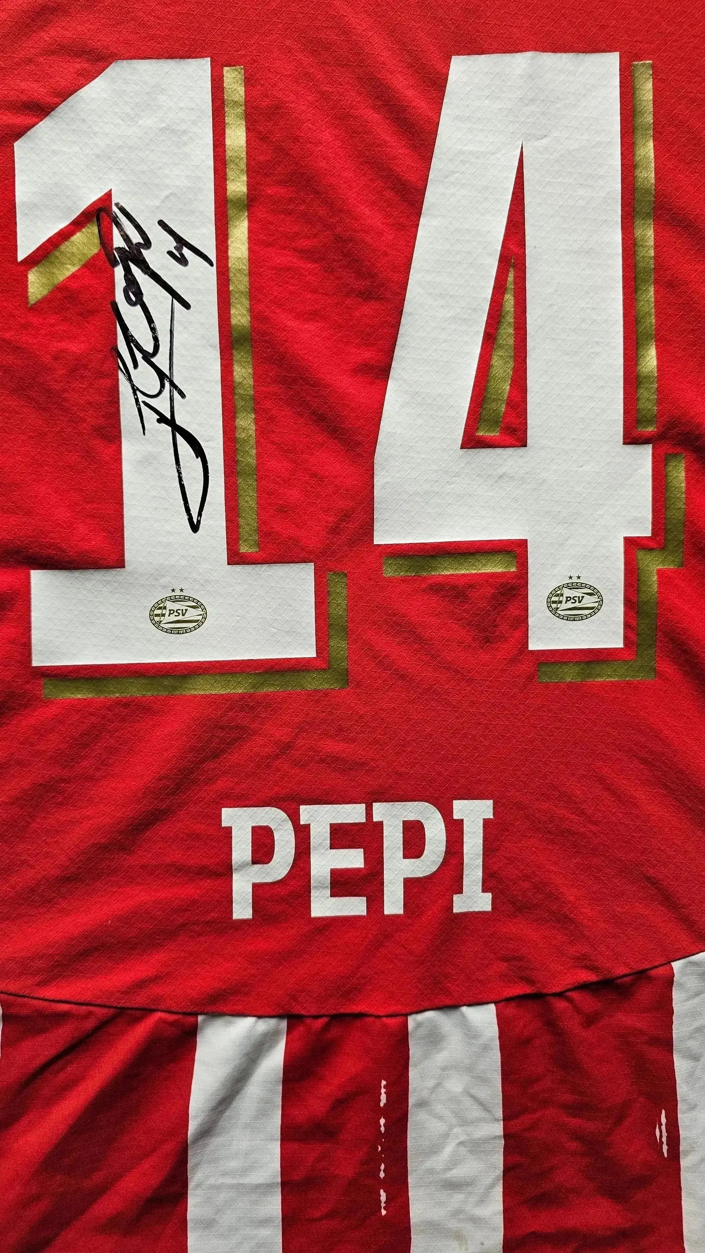 Close-up of No. 14 with signature and name 'PEPI' on a red PSV Eindhoven football shirt.