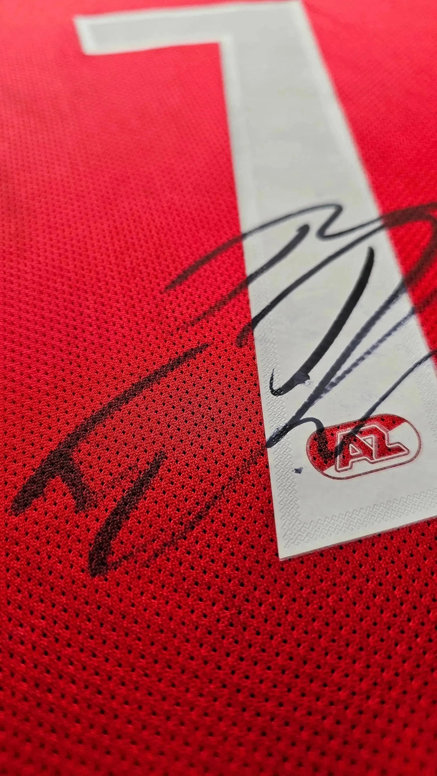 Close-up showing signature detail of the number 7 on a red football shirt with AZ Alkmaar logo.