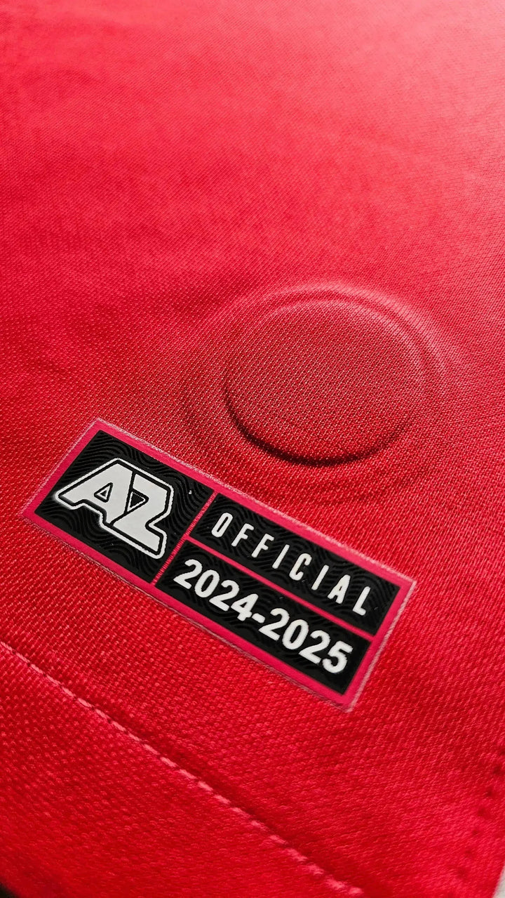 Detail view showing AZ crest, 'OFFICIAL', and '2024-25' on a red football shirt.
