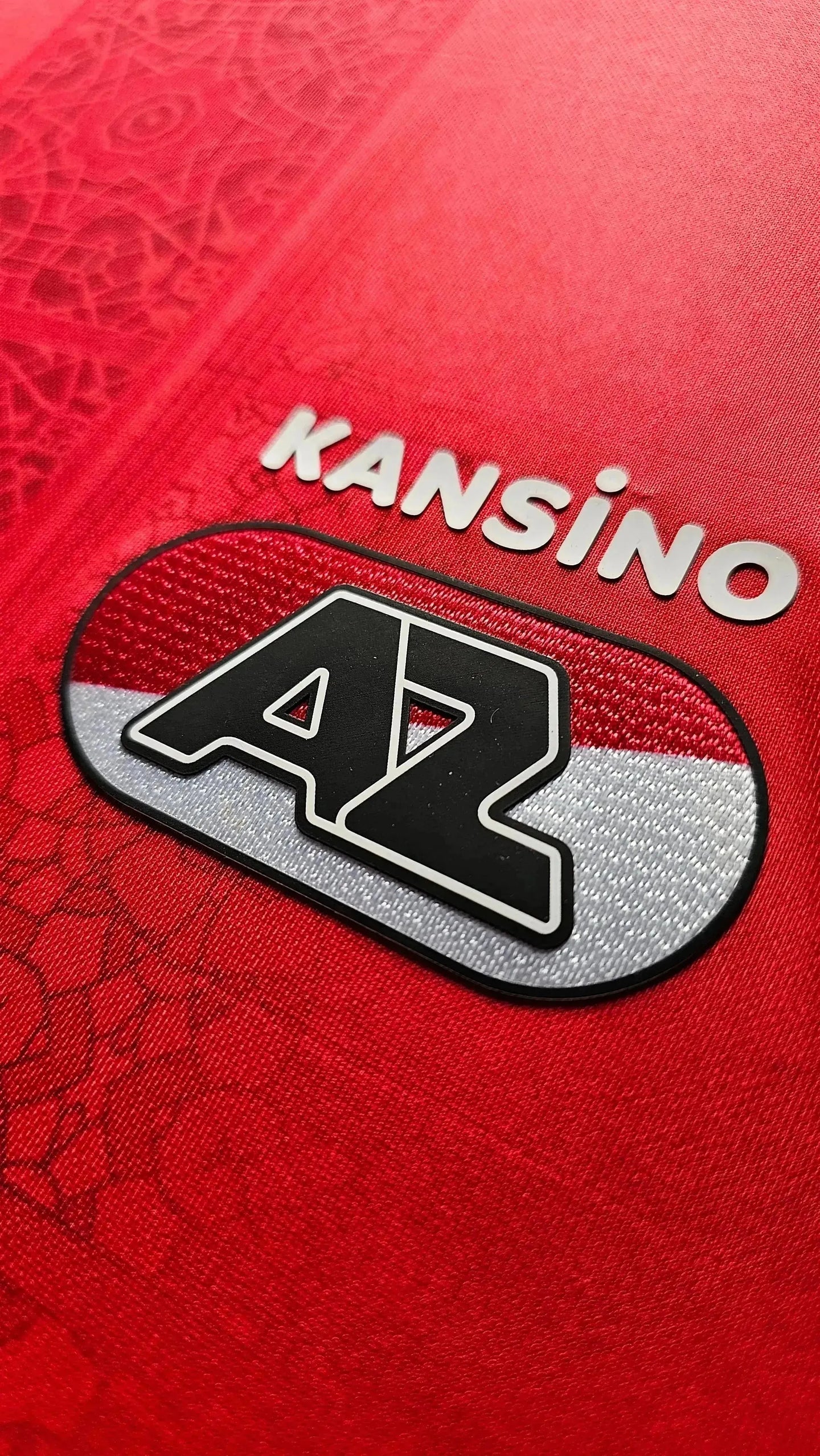 Crest detail featuring AZ Alkmaar logo and Kansino sponsor on a red background.
