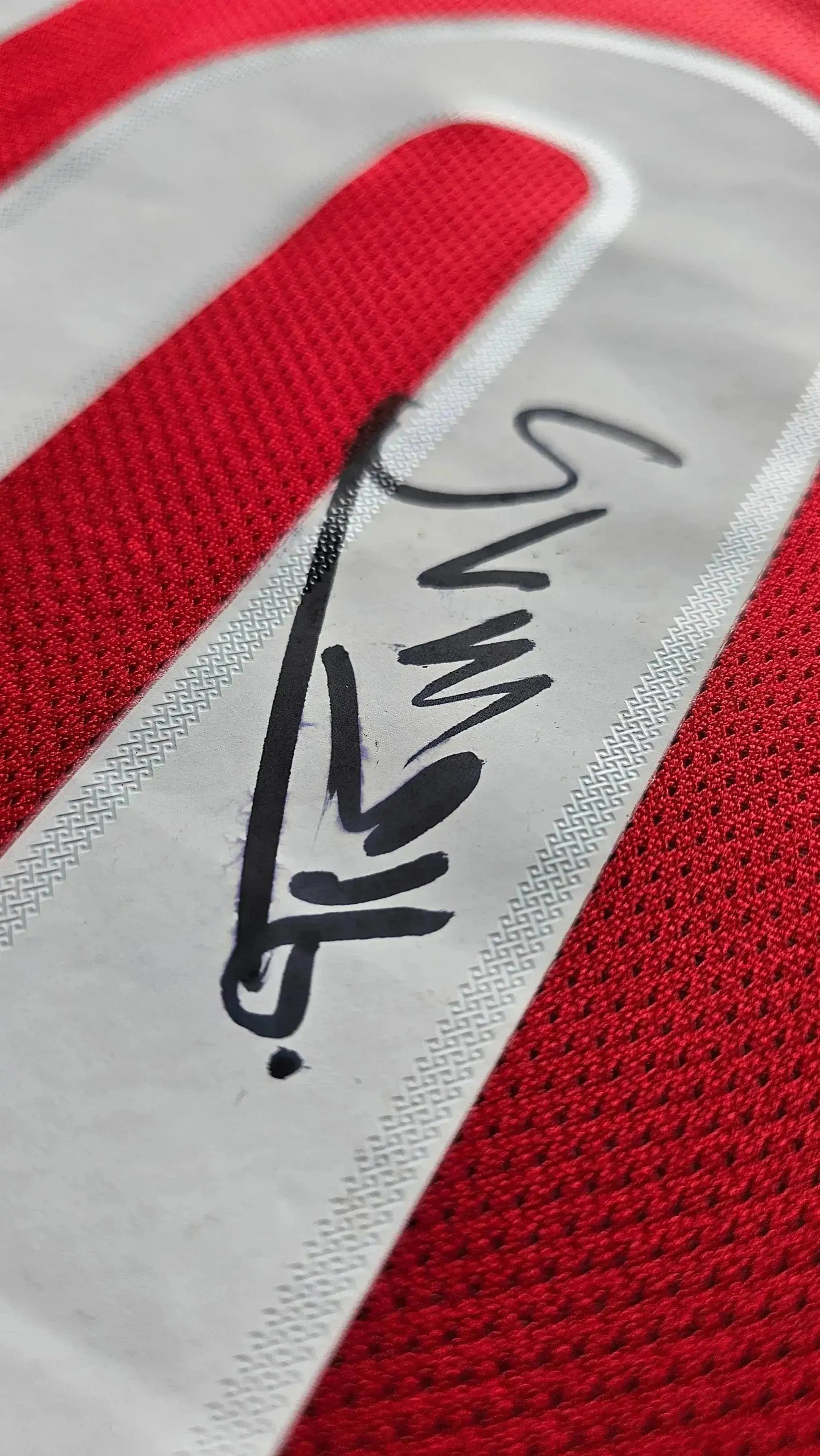 Sven Mijnans signature on the white strip of a red football shirt.