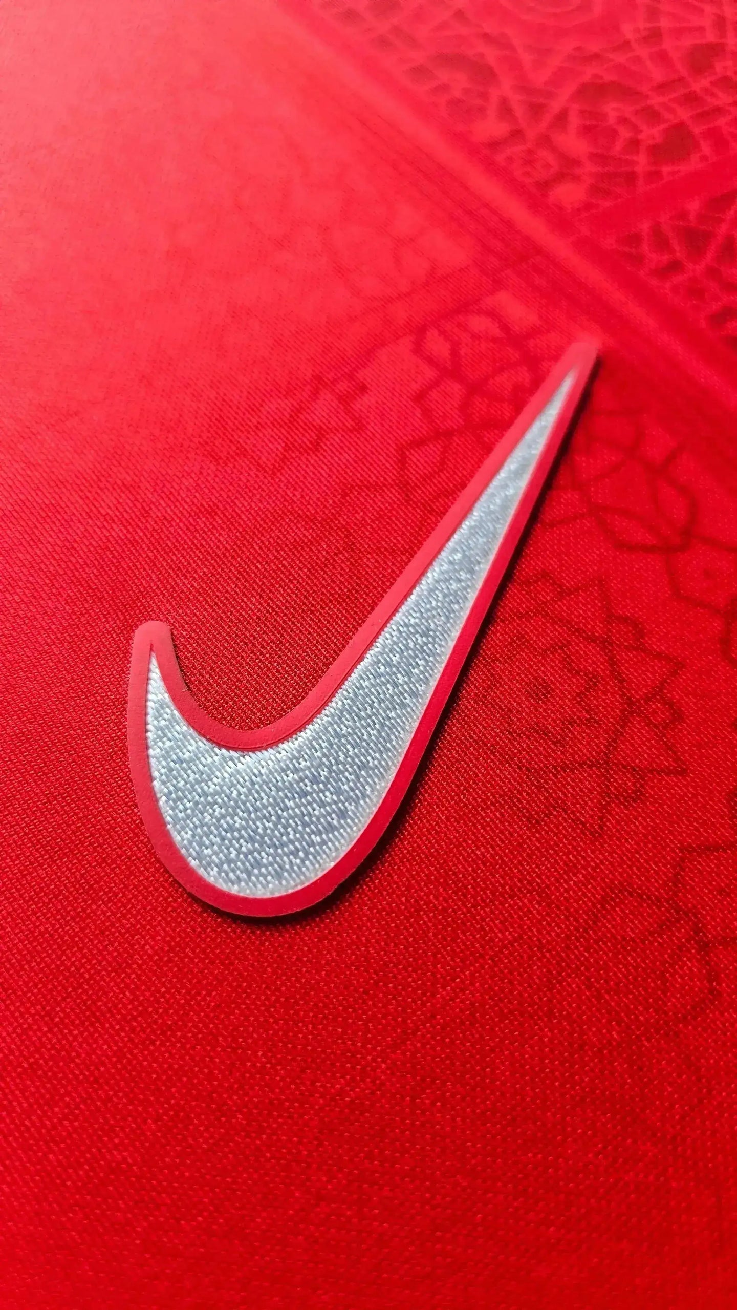 Close-up of the Nike logo in silver on a red AZ Alkmaar football shirt.