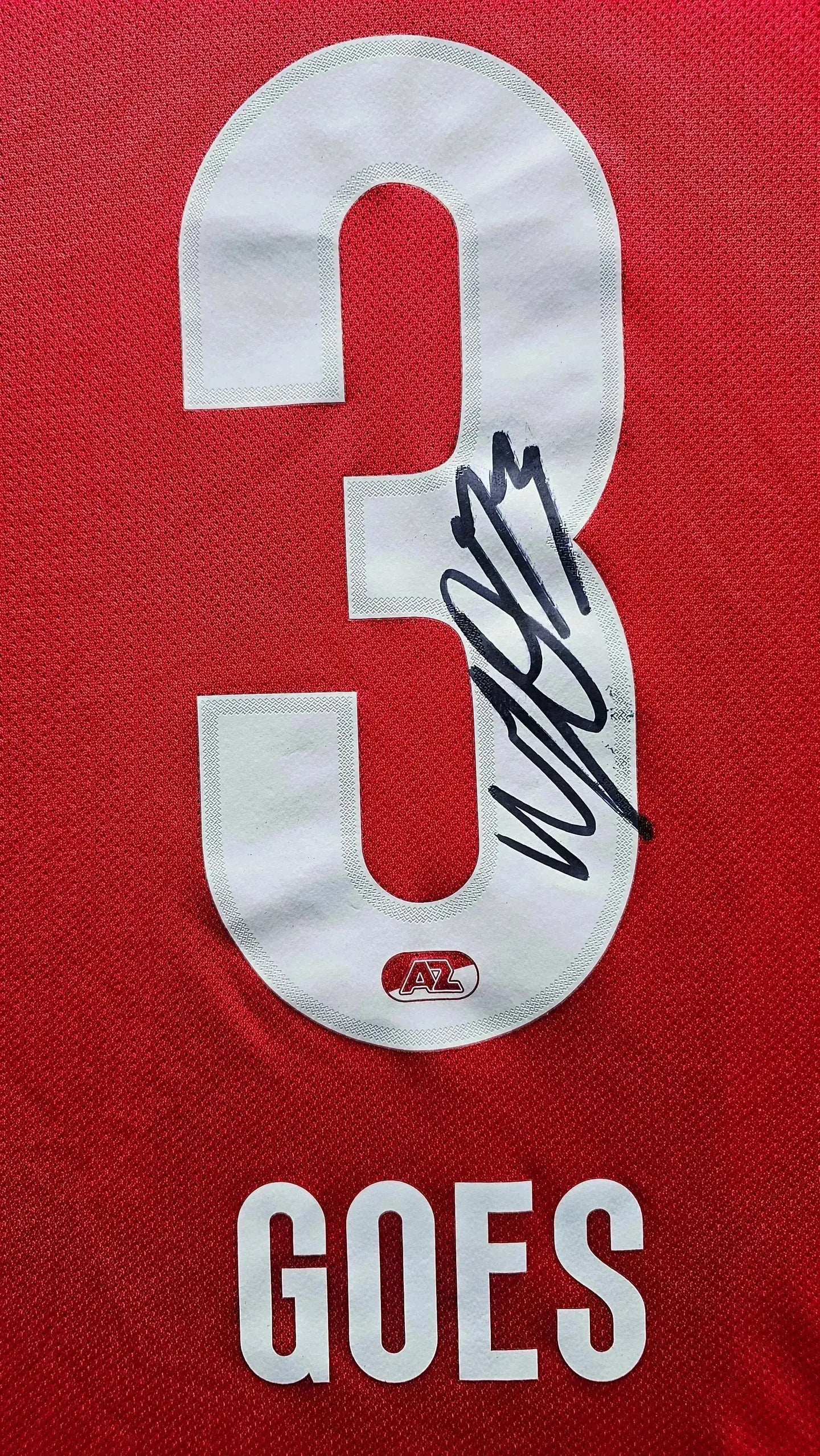 Detail showing No. 3 and signature of Wouter Goes on a red AZ Alkmaar football shirt.