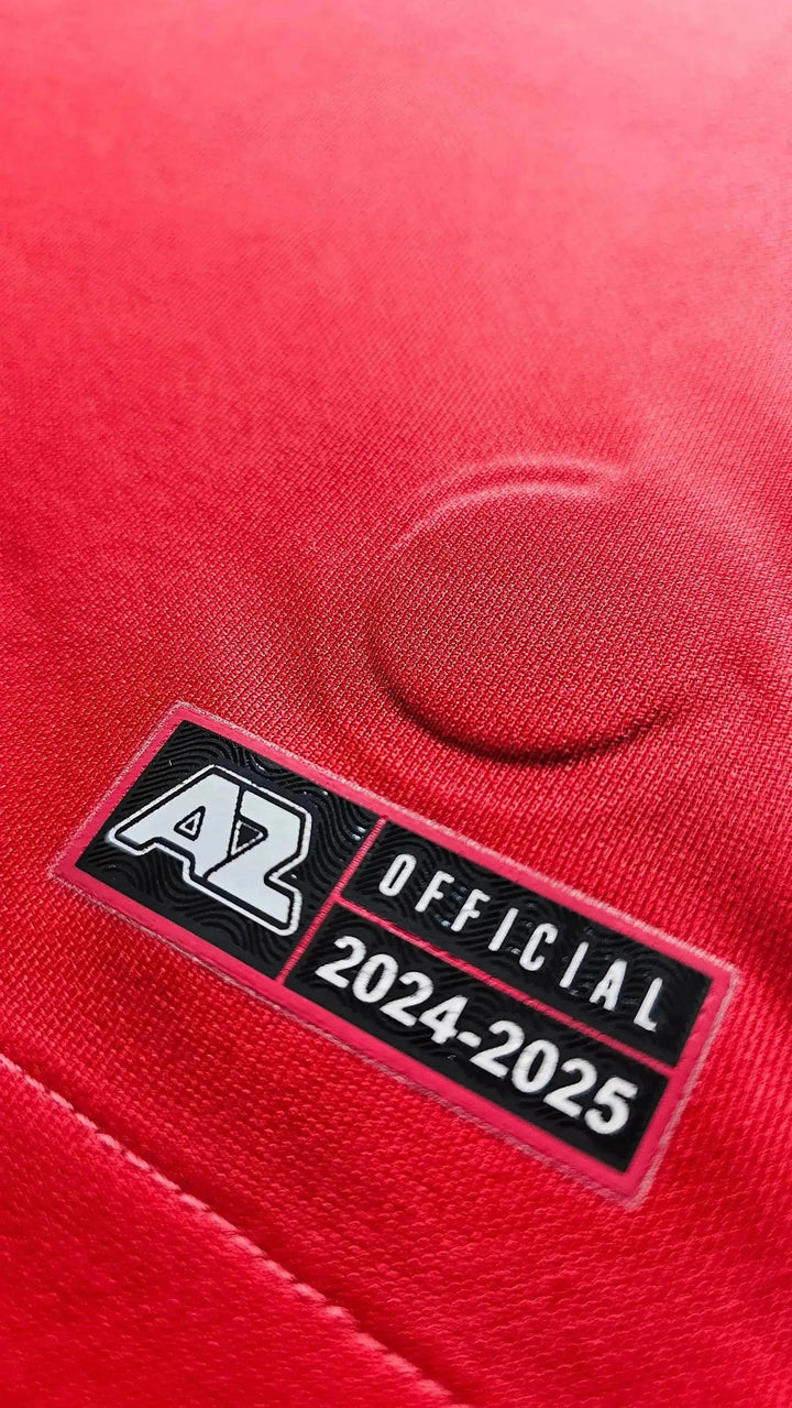 Crest detail featuring AZ logo and badge with text 'OFFICIAL 2024-25' on red background.