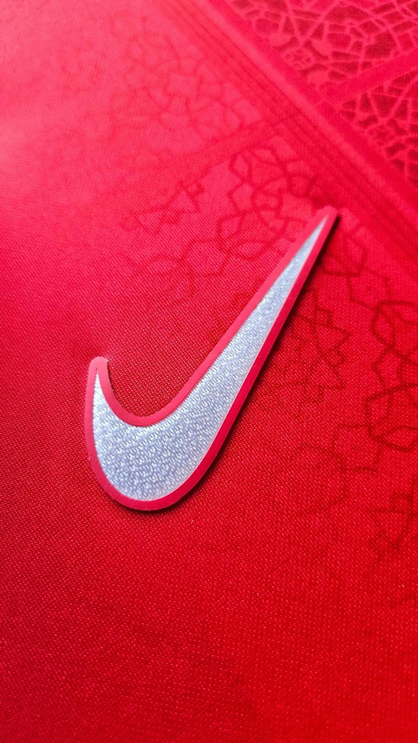 Close-up of red fabric featuring Nike logo detail on signed football shirt.