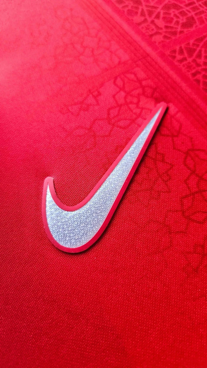 Close-up of red fabric featuring Nike logo detail on signed football shirt.