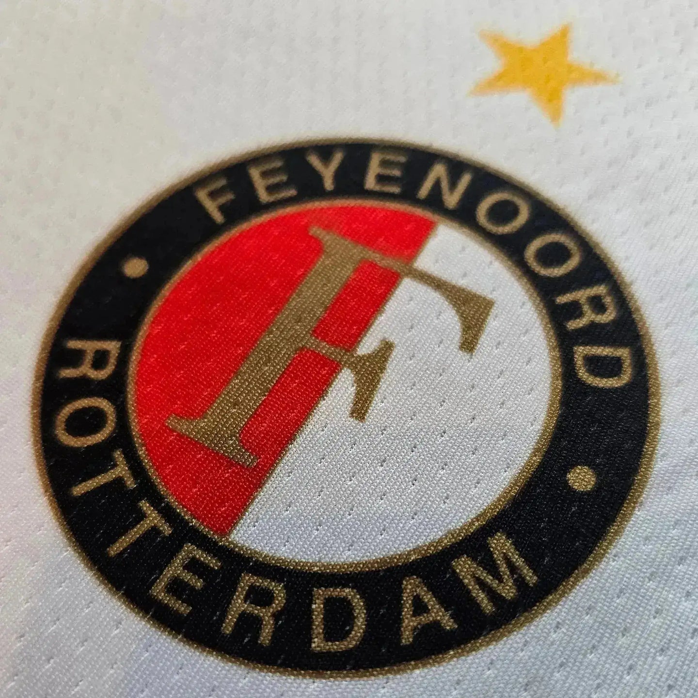 Close-up of Feyenoord Rotterdam crest featuring gold star and red, white, and black colors.