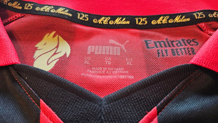 Detail view showing AC Milan 125th Anniversary crest and Puma branding on the signed football shirt.