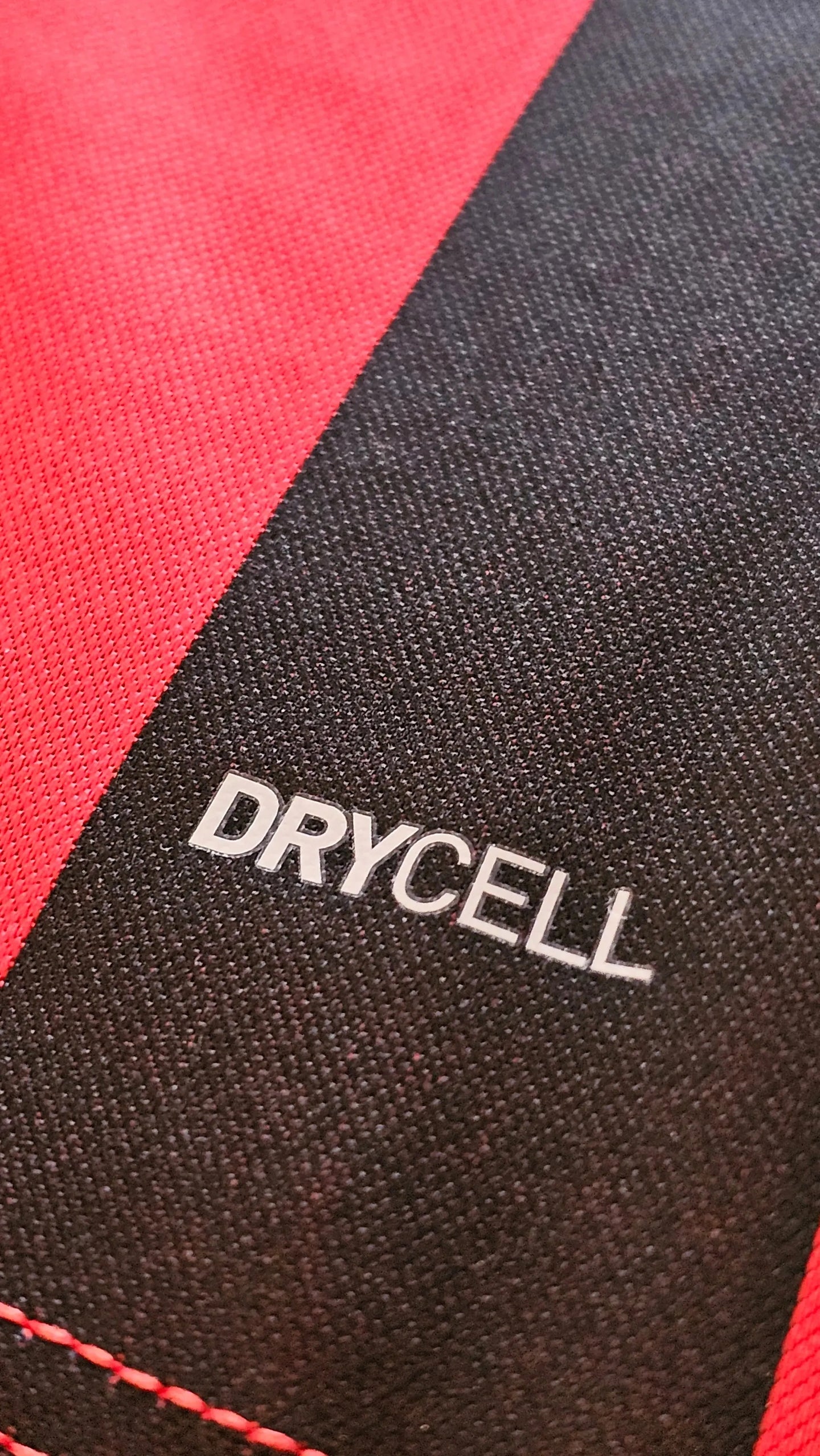 Close-up showing DRYCELL text on red and black striped football shirt fabric.
