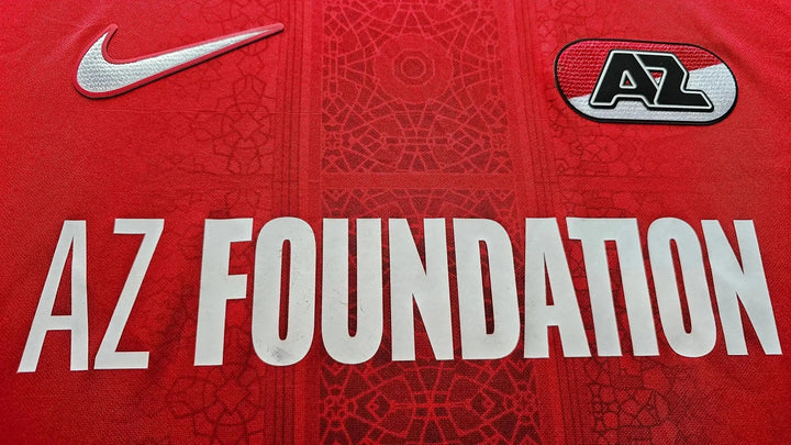 Detail view featuring the AZ Foundation logo and Nike swoosh on a red football shirt.