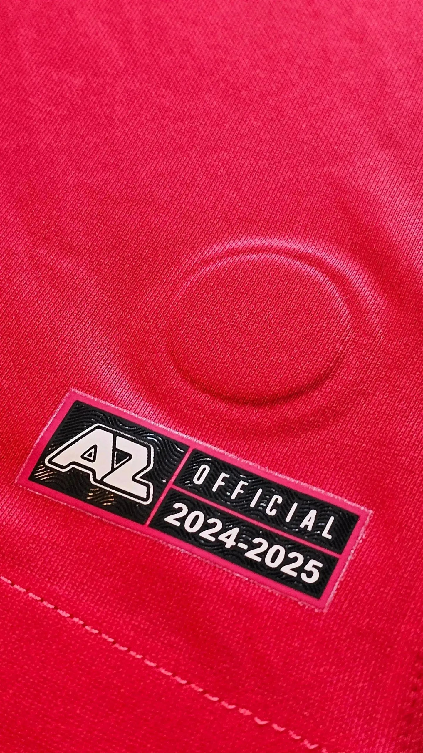 Close-up of AZ Alkmaar tag featuring 'OFFICIAL' and '2024-2025' on a red football shirt.