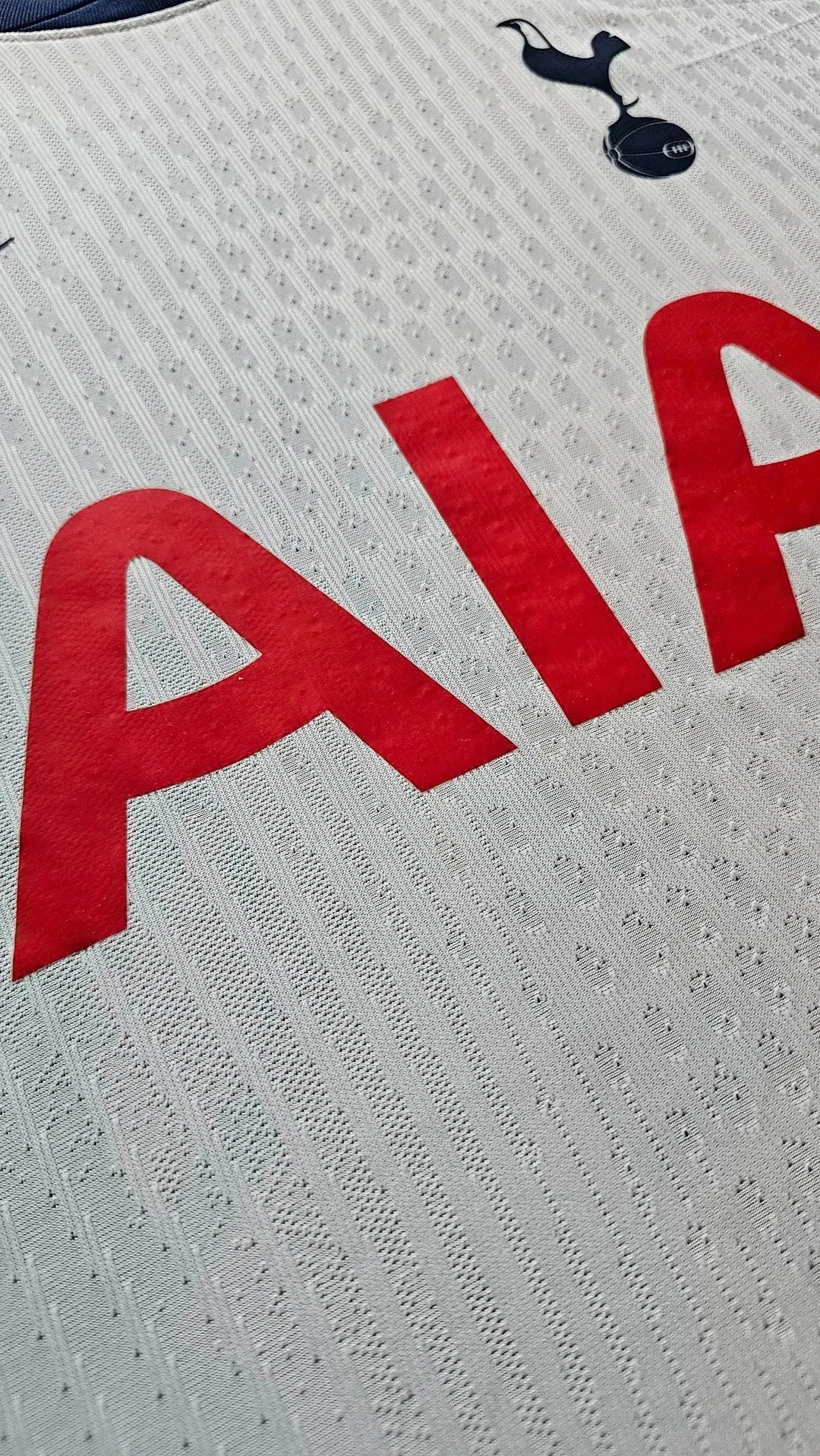 Detail view highlighting the red 'AIA' sponsor text on a Tottenham Hotspur football shirt.