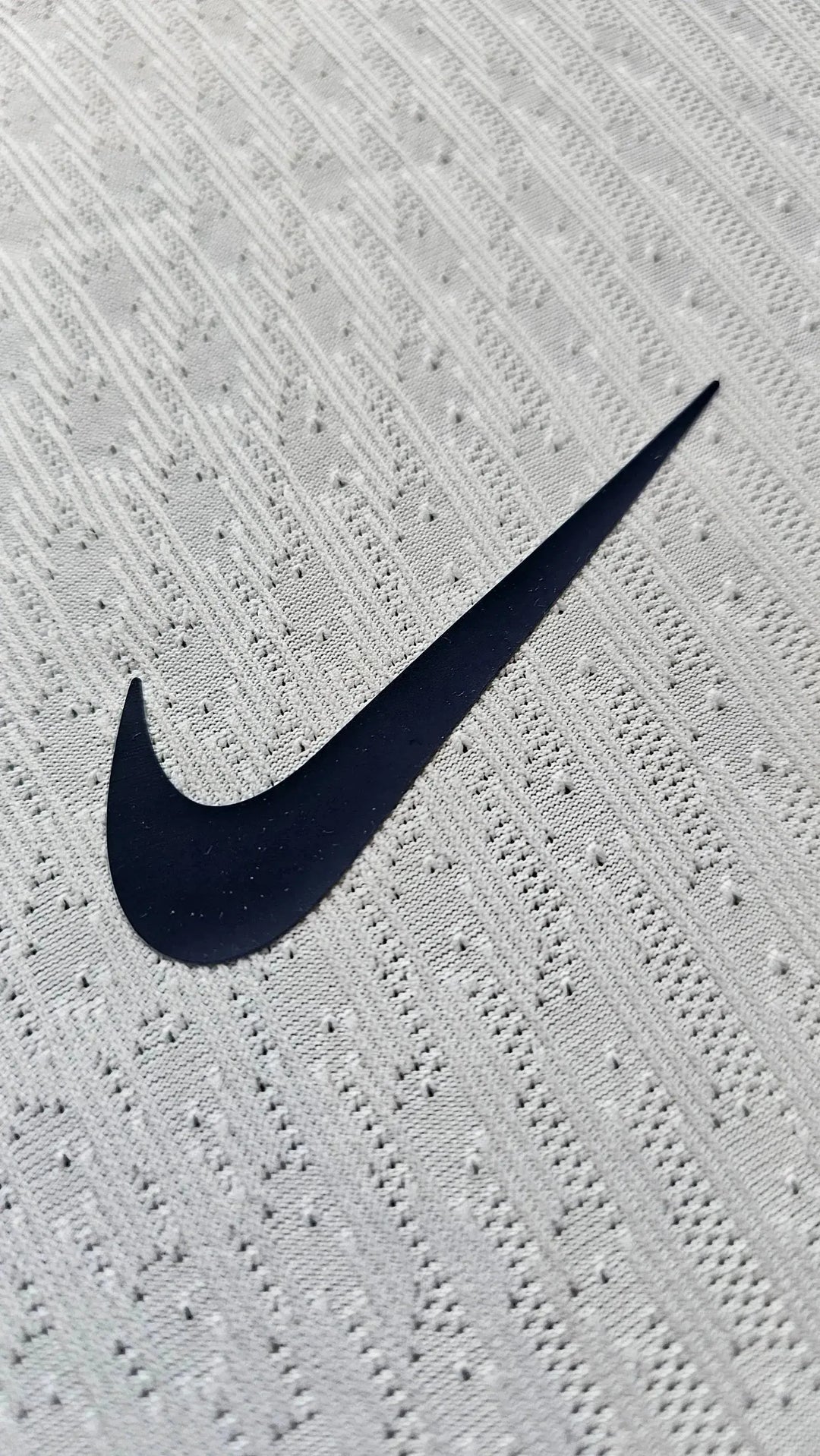 Nike logo detail on white fabric with textured pattern.