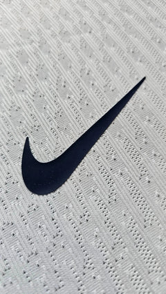 Nike logo detail on white fabric with textured pattern.