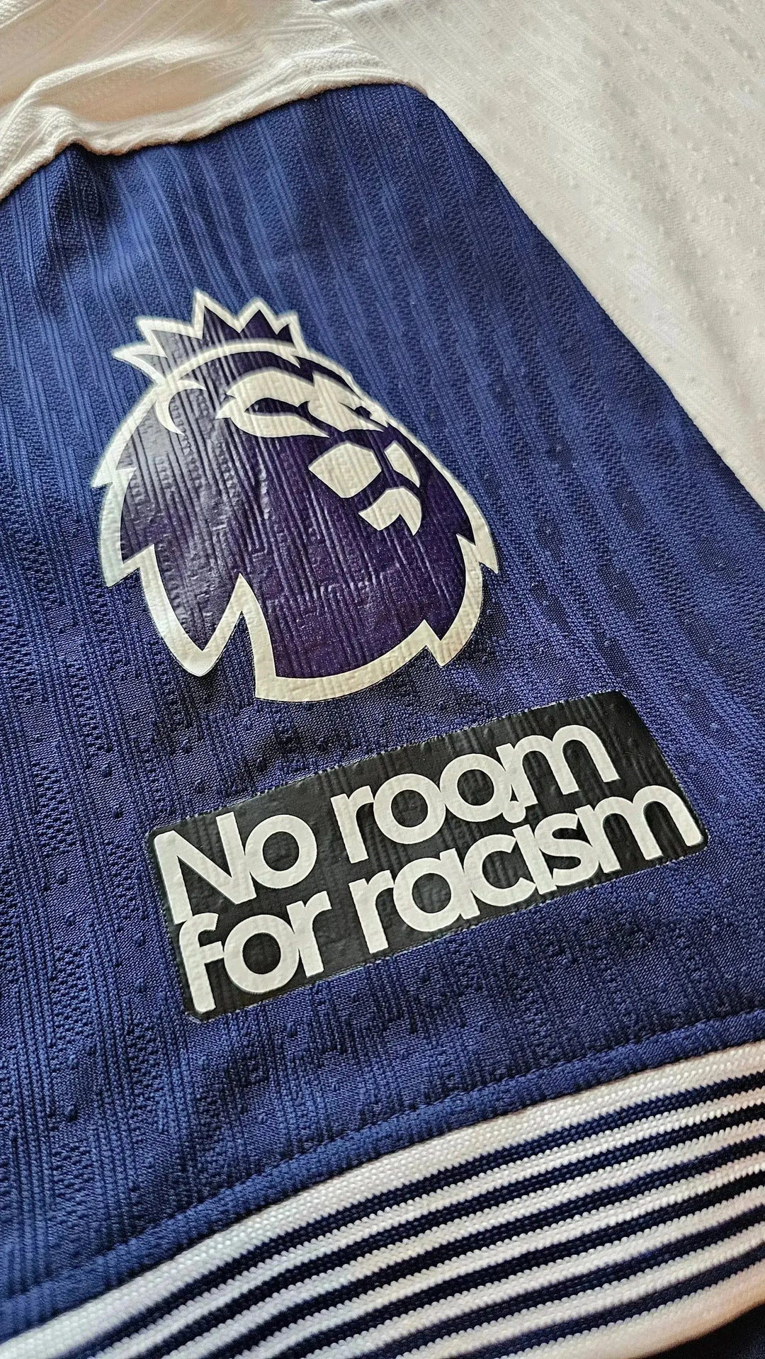 Close-up view showing the Premier League lion crest and 'No room for racism' message.