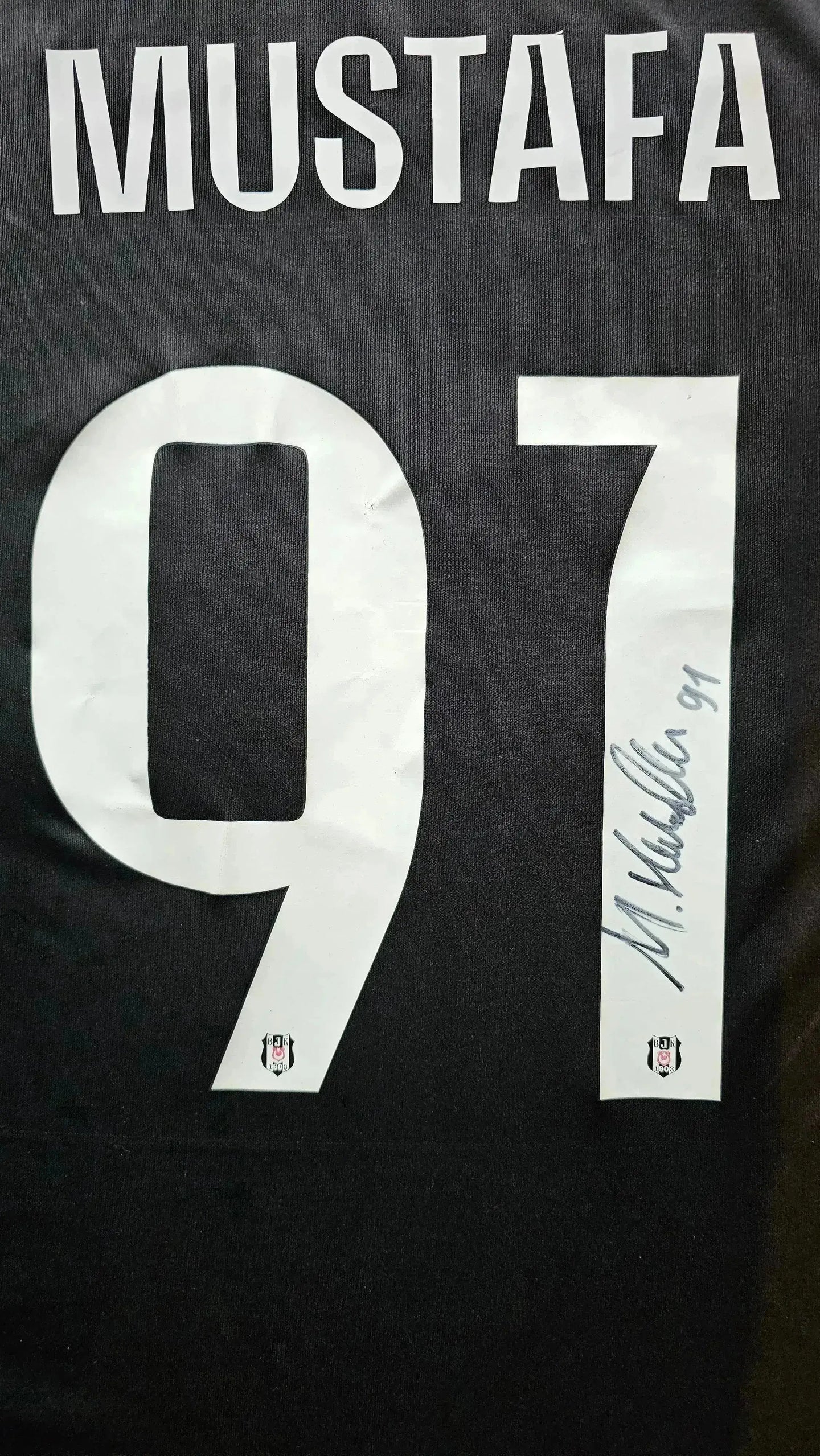 Back view showing name Mustafa and No. 91 with a signature next to the number.