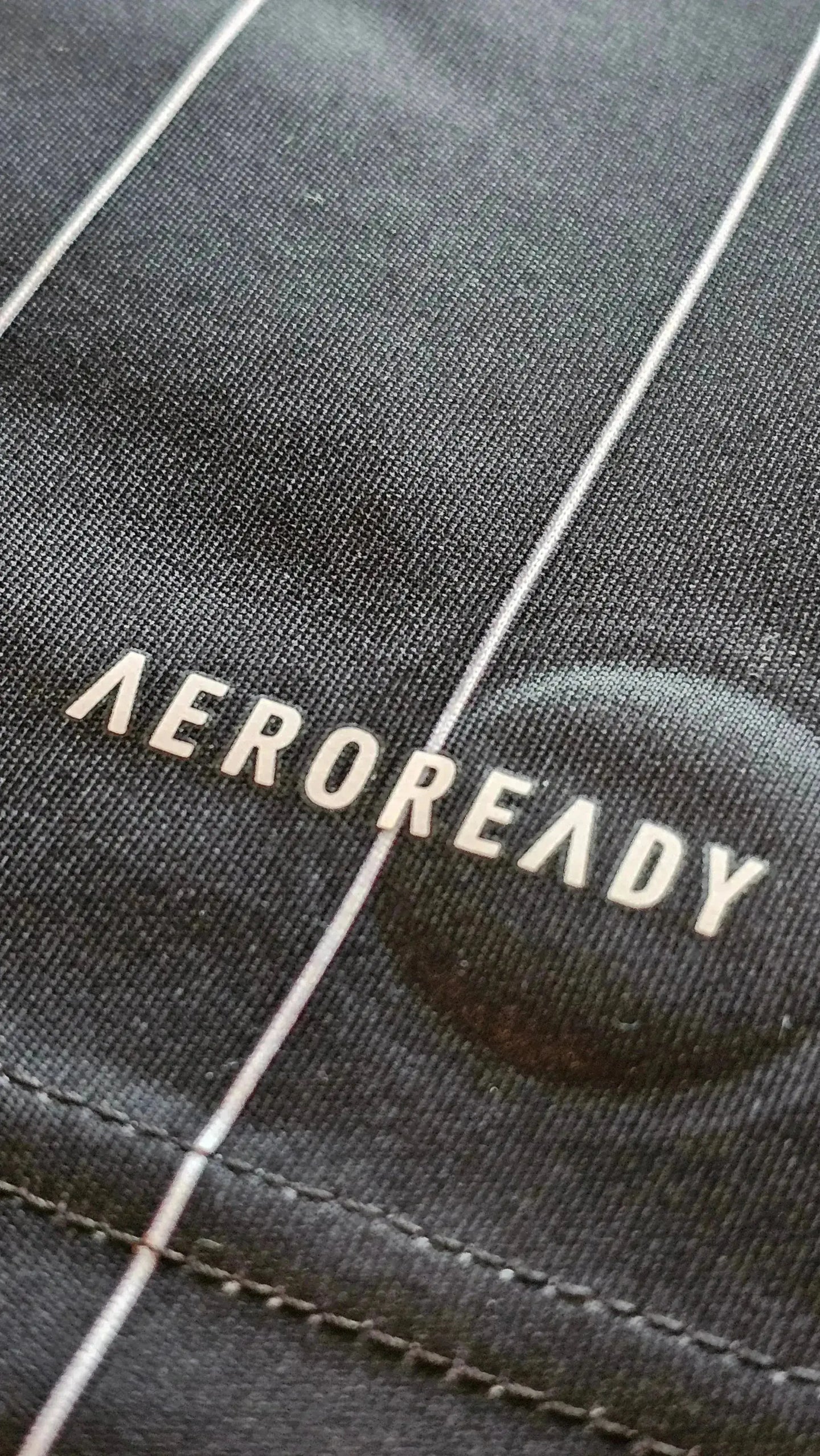 Close-up of AEROREADY branding on black fabric with white stitching detail.