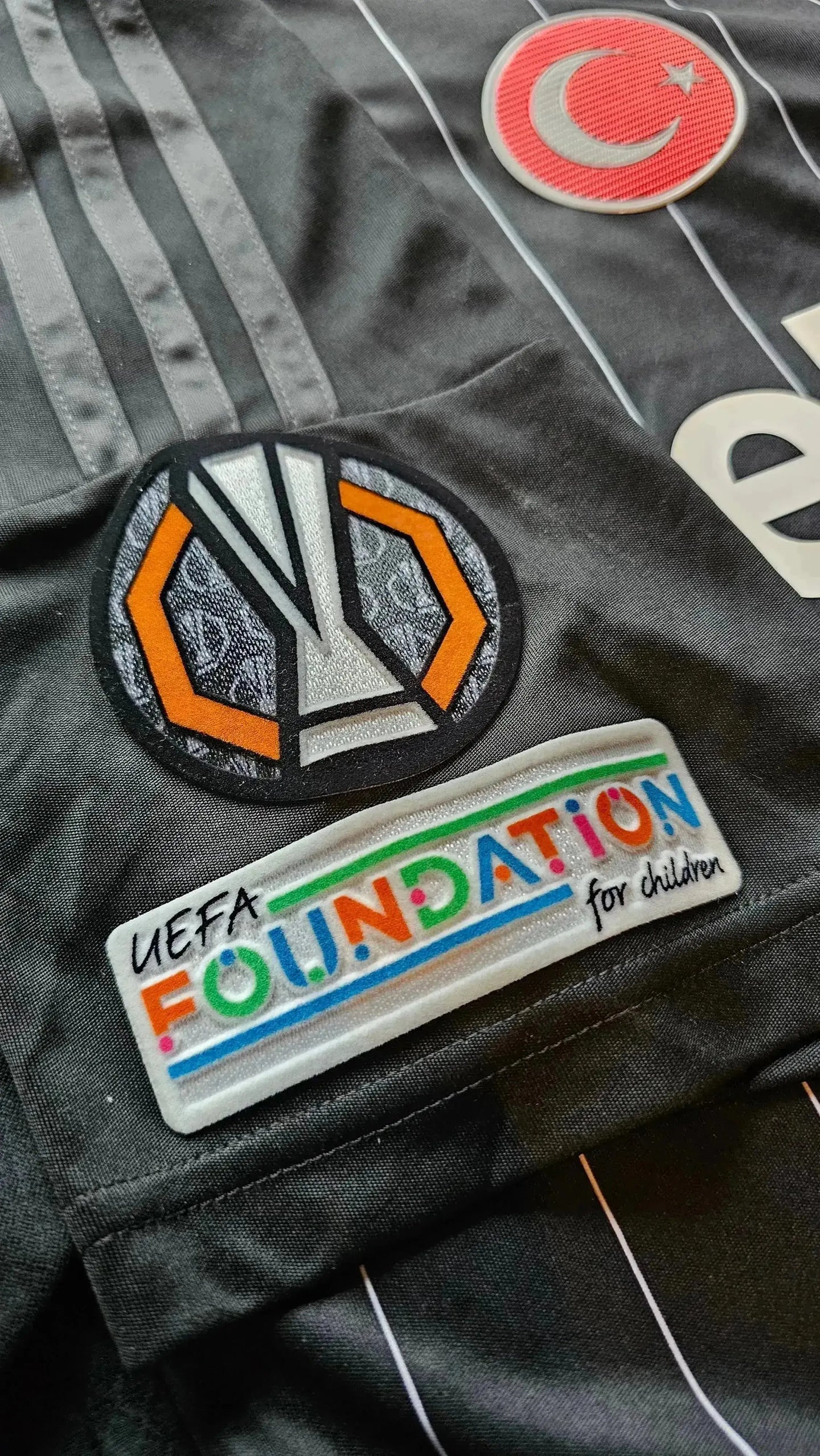 Close-up of UEFA Foundation for children and UEFA patch on Beşiktaş shirt.