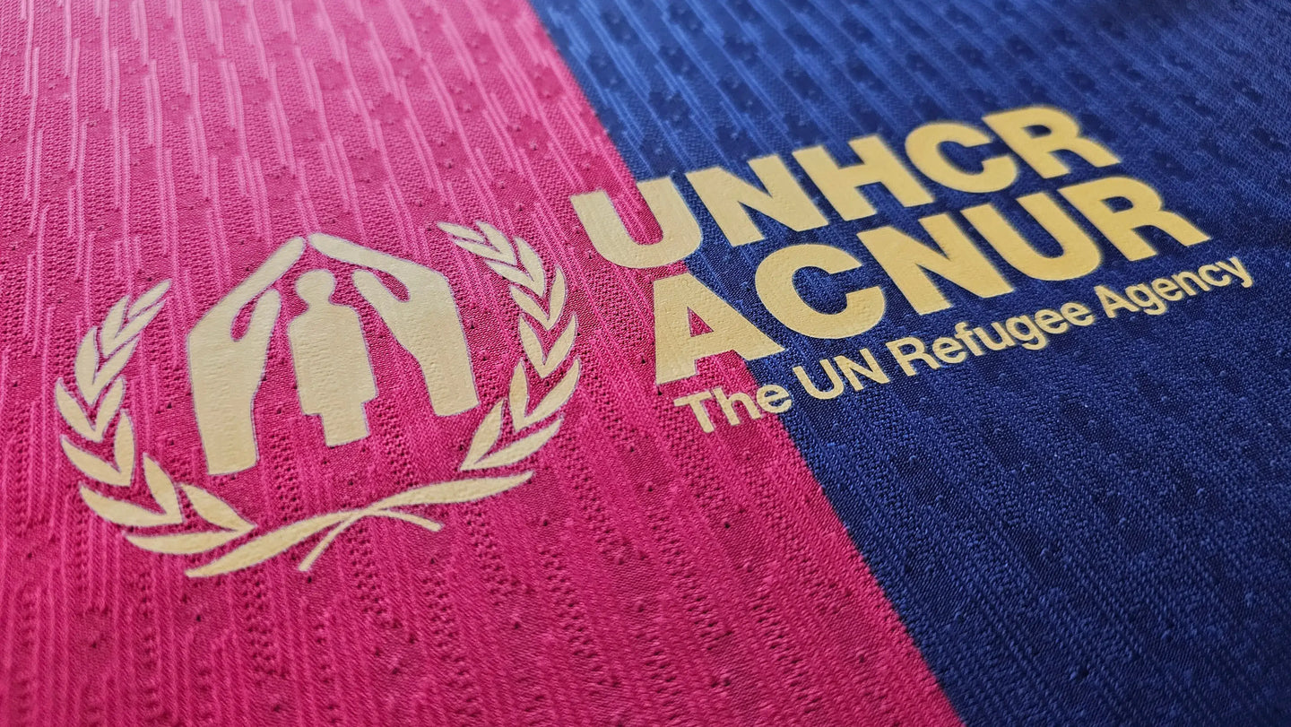 Close-up of Barcelona jersey detail featuring UNHCR ACNUR logo and text The UN Refugee Agency.