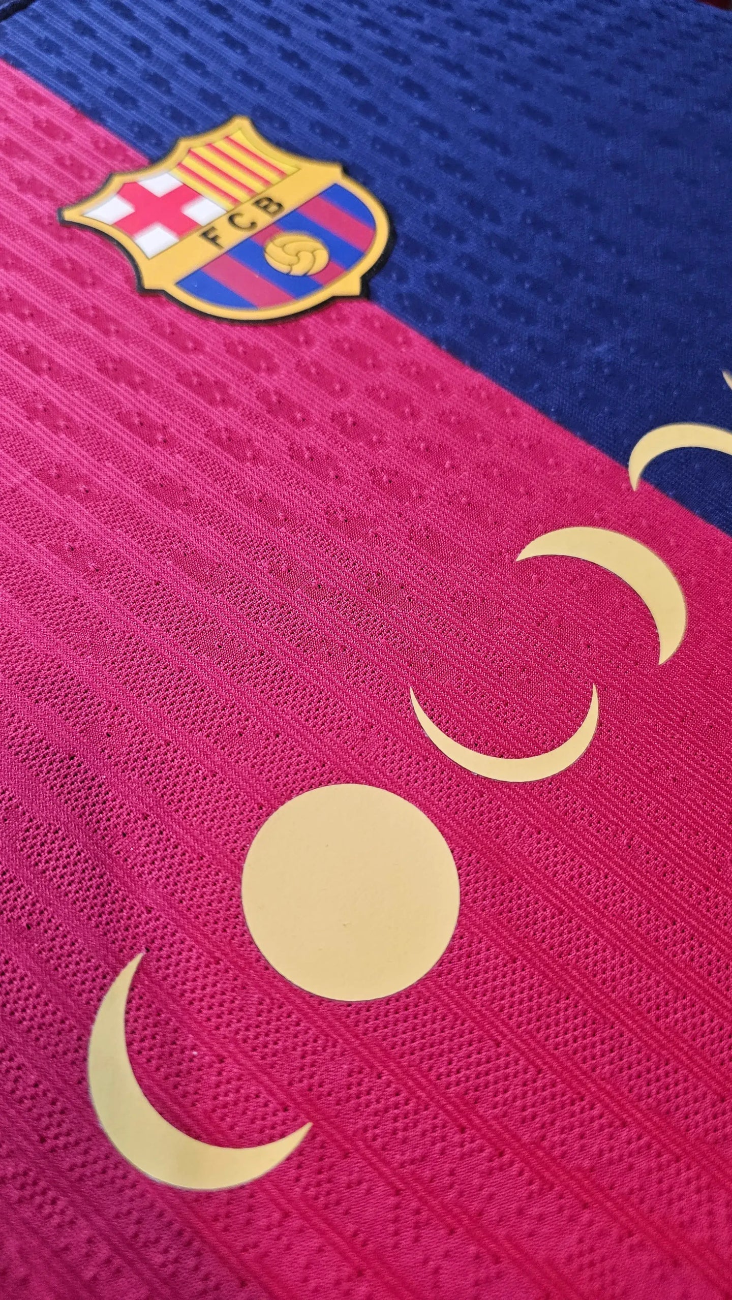Close-up of FC Barcelona crest on a blue and red football shirt with yellow details.