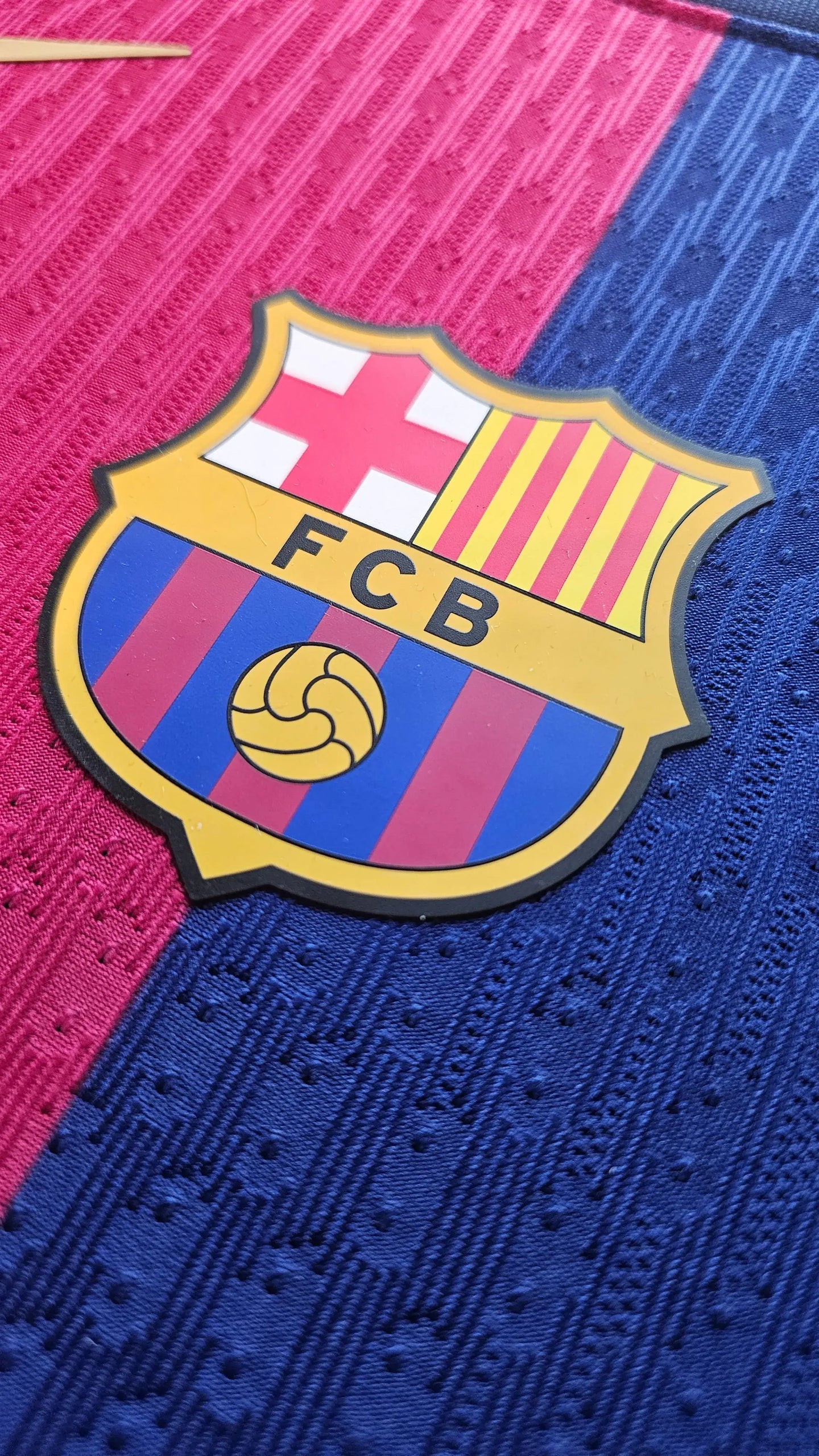 Close-up view of FC Barcelona crest featuring red and blue colors with striped design and soccer ball.
