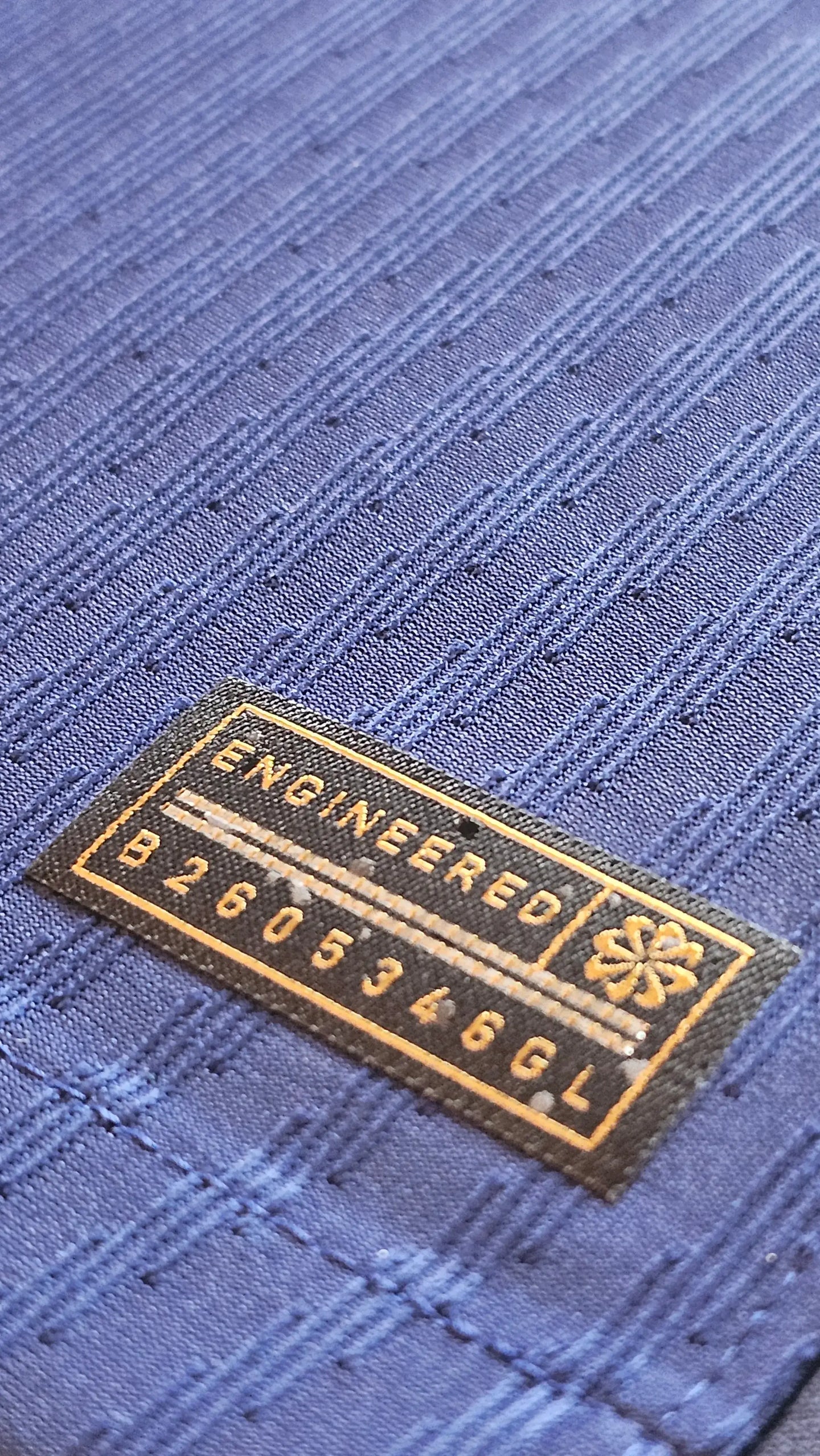 Close-up detail showing 'ENGINEERED' label and code B2605346GL on blue fabric.