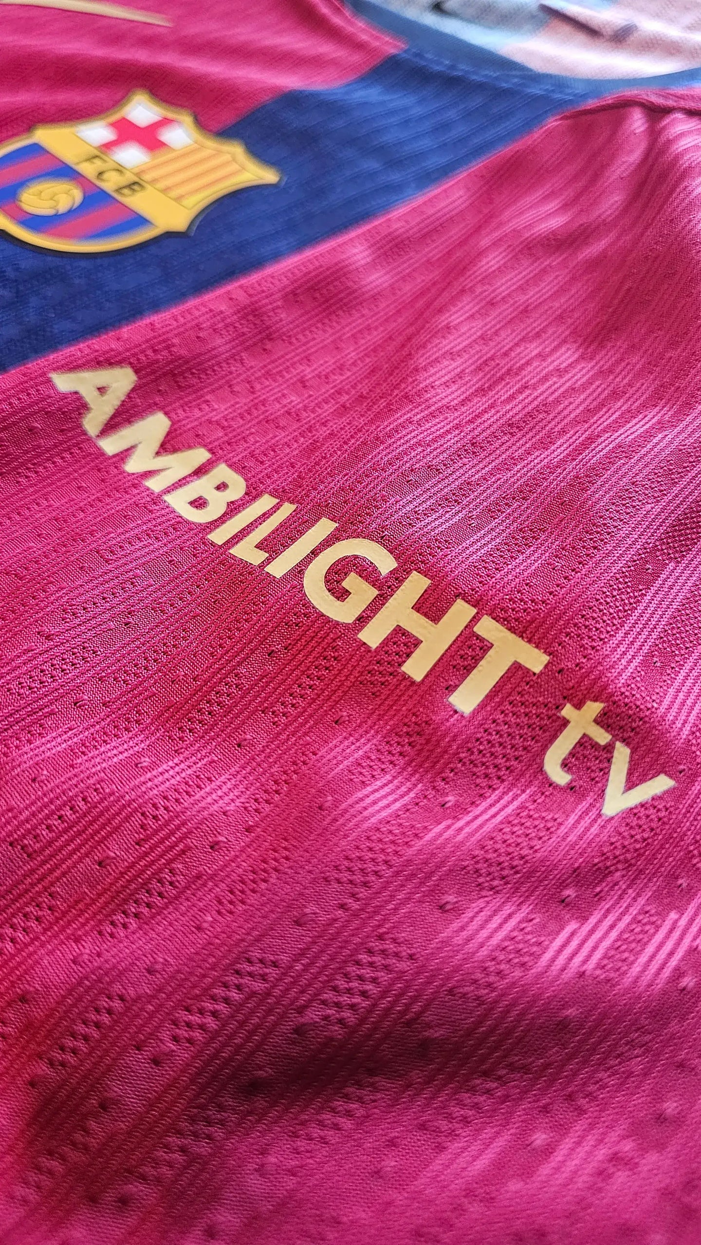 Detail showing the FC Barcelona crest and AMBILIGHT tv sponsor in gold on a red background.
