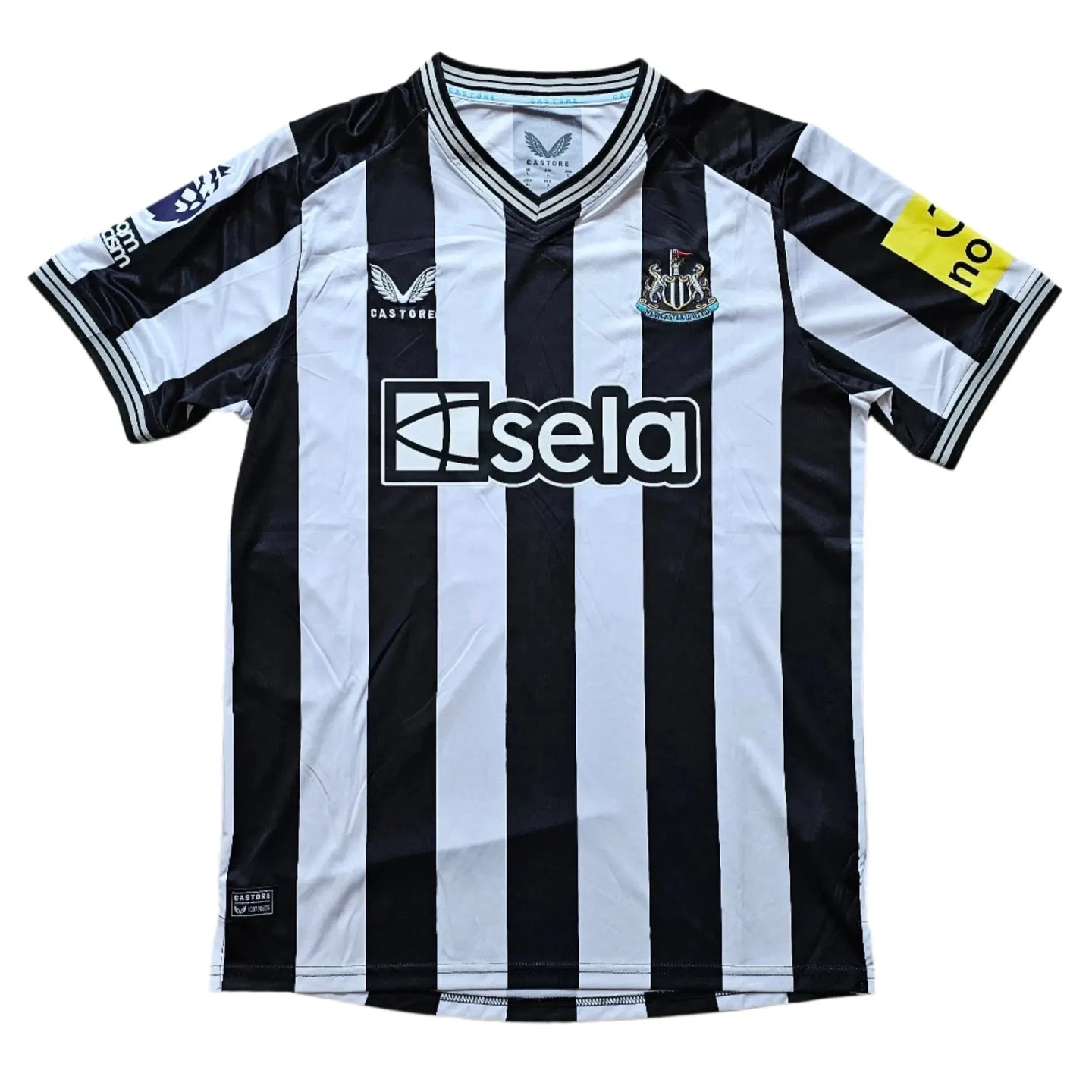 Front view of Newcastle football shirt with black and white stripes and visible sponsor 'sela'.