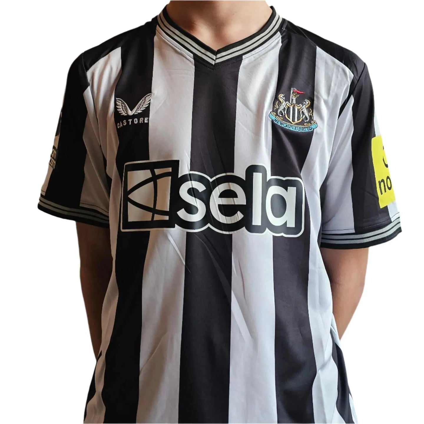Front view of signed Newcastle football shirt featuring black and white stripes and the crest.