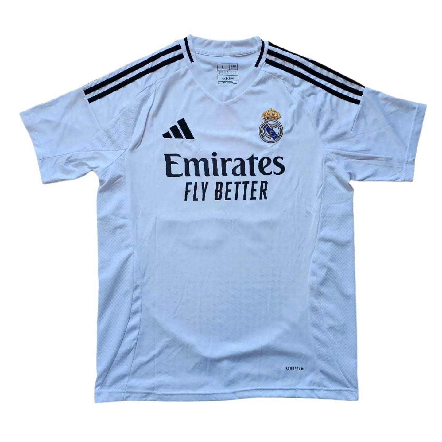 Front view of white football shirt featuring Real Madrid crest and 'Emirates Fly Better' sponsor.