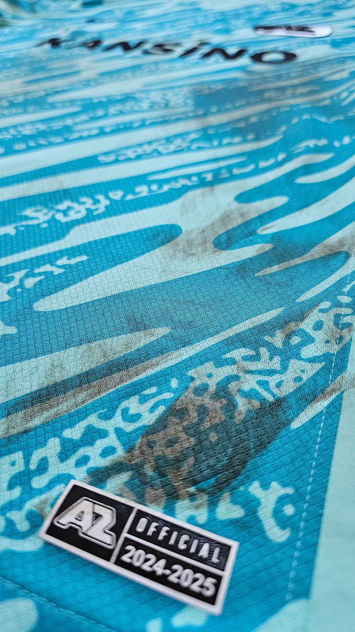 Detail view of AZ Alkmaar crest tag with text 'A2 OFFICIAL 2024-25' on a blue background.
