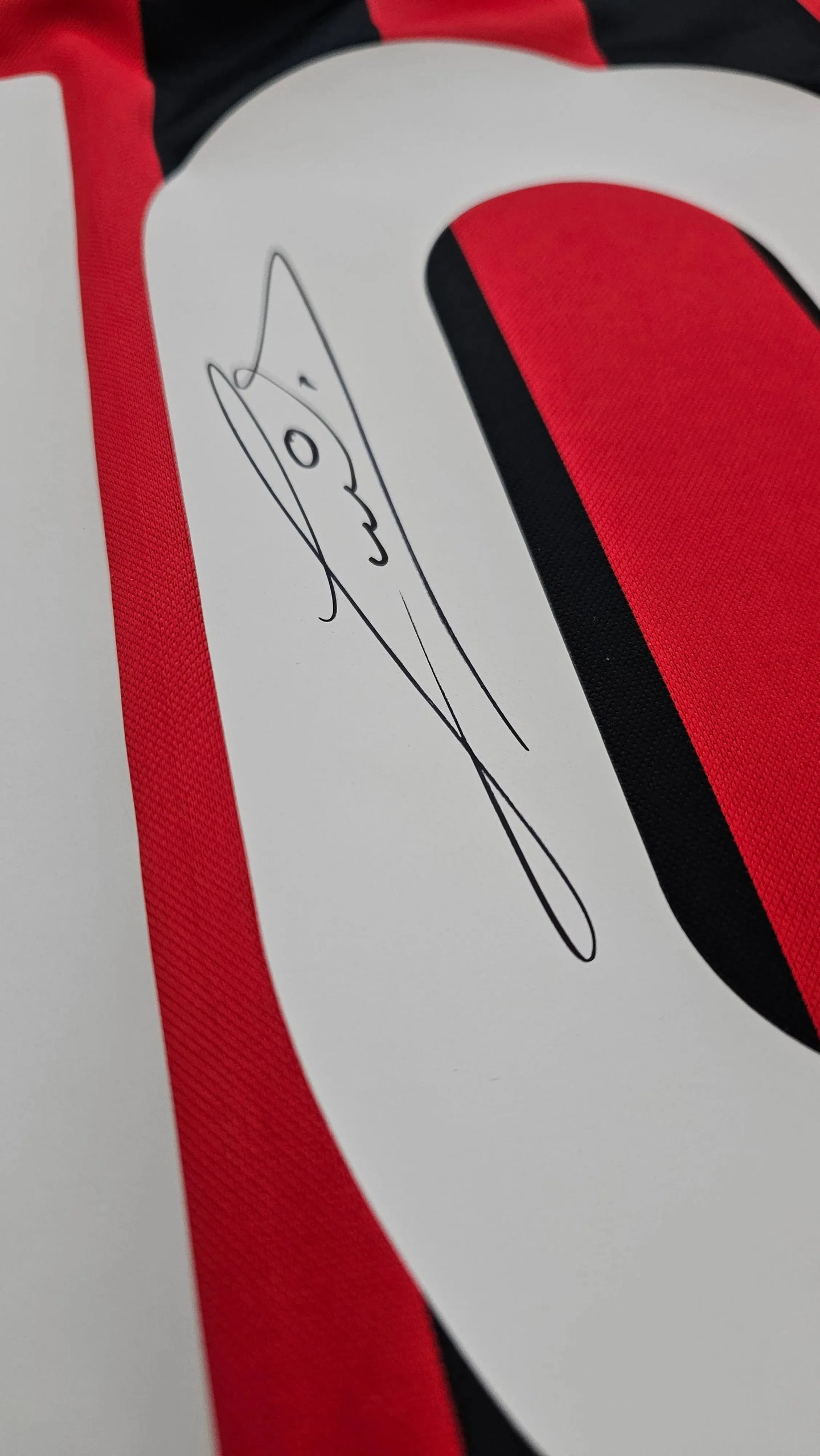 Close-up of signature detail on Ruud Gullit No. 10 AC Milan soccer jersey with red and black stripes.
