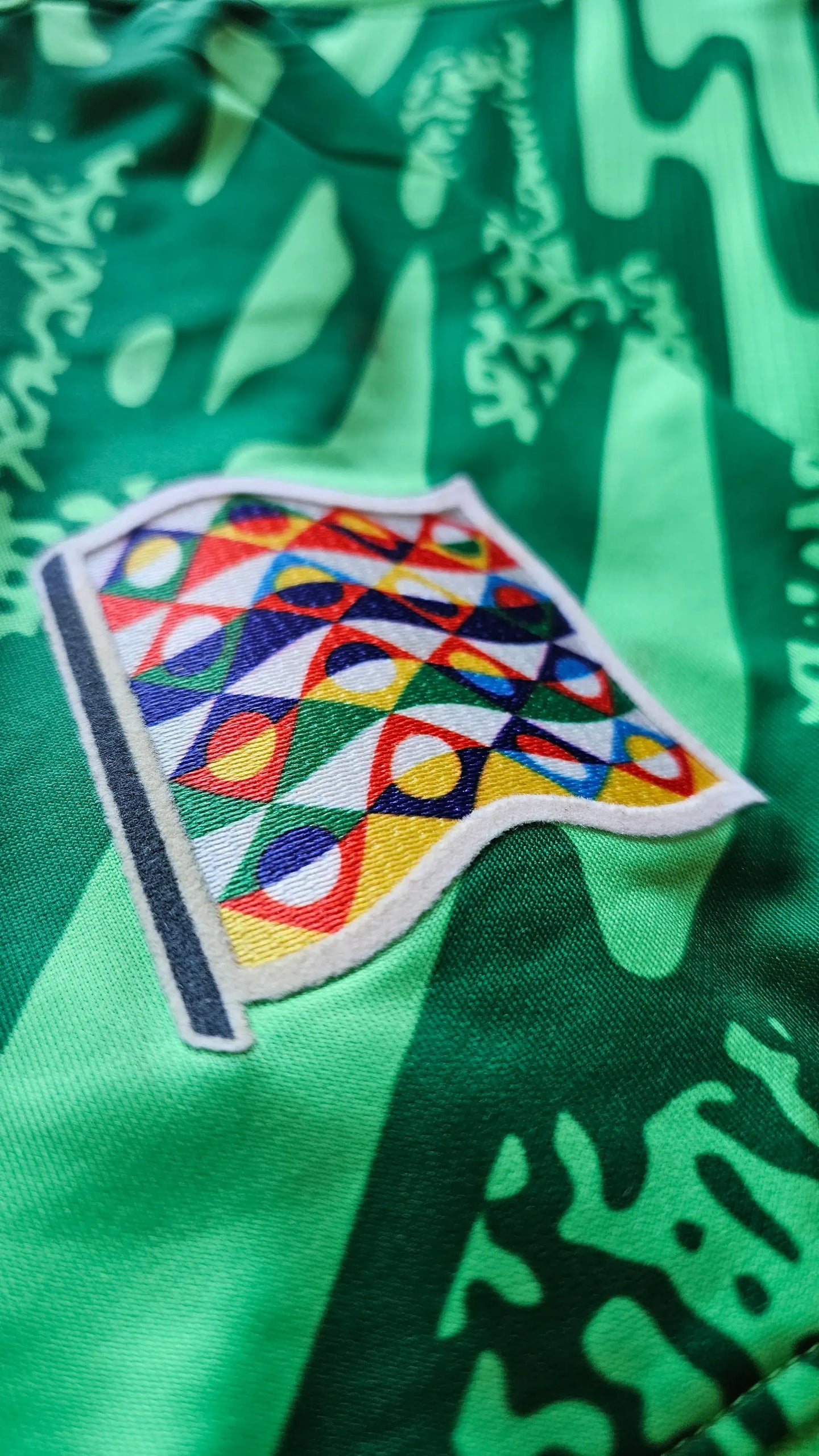 Crest detail featuring colorful geometric patterns on a green background.