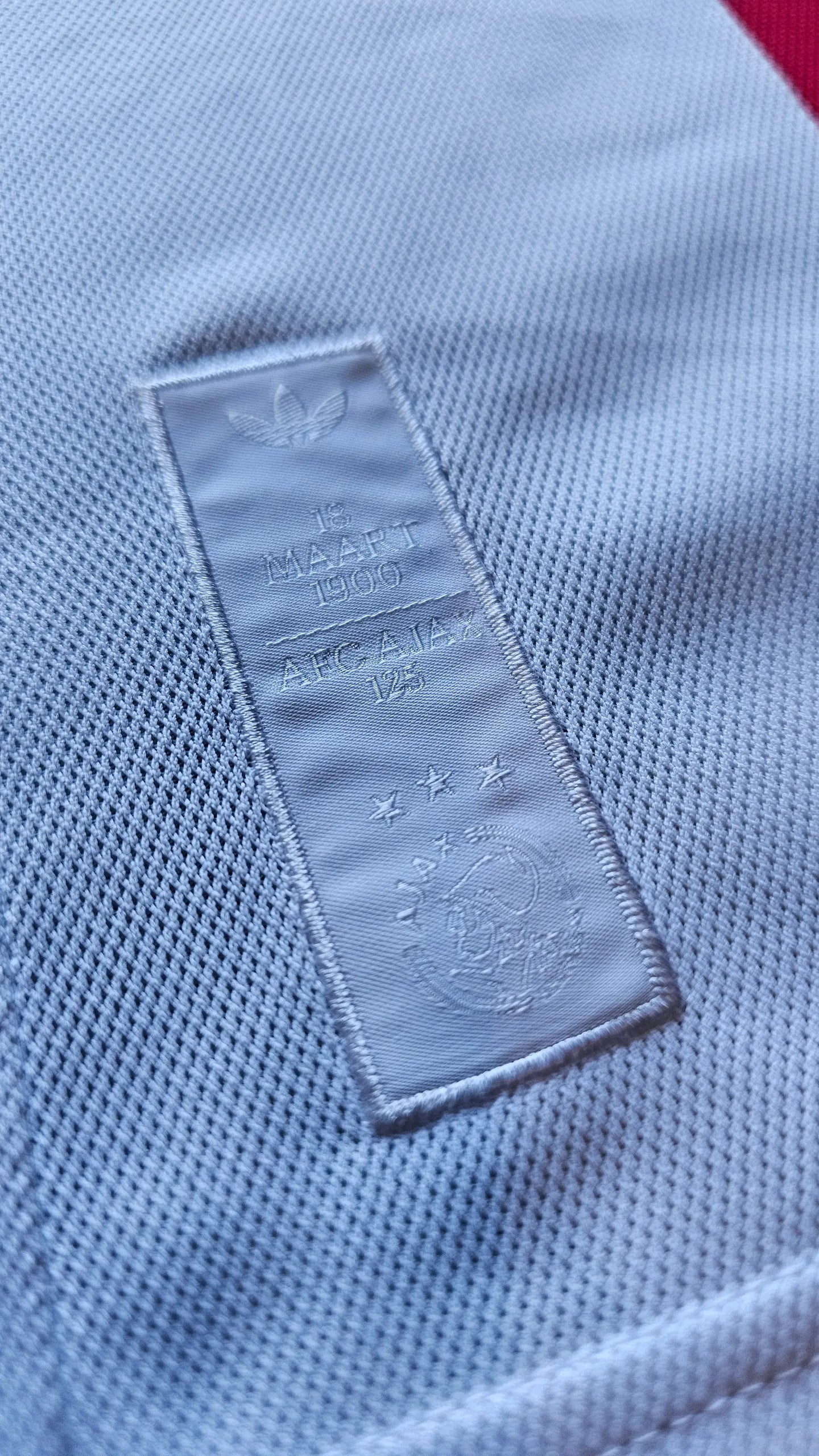 Crest detail showing AFC Ajax, 125 years, three stars and '18 MAART 1900' inscription.