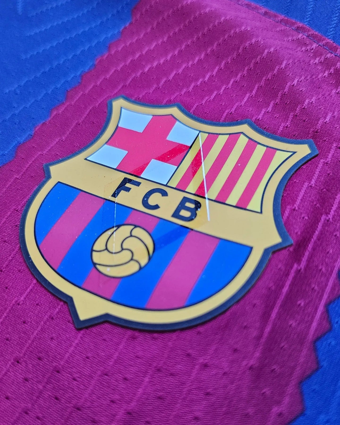 Crest detail of FC Barcelona featuring blue and red stripes with the FCB logo.