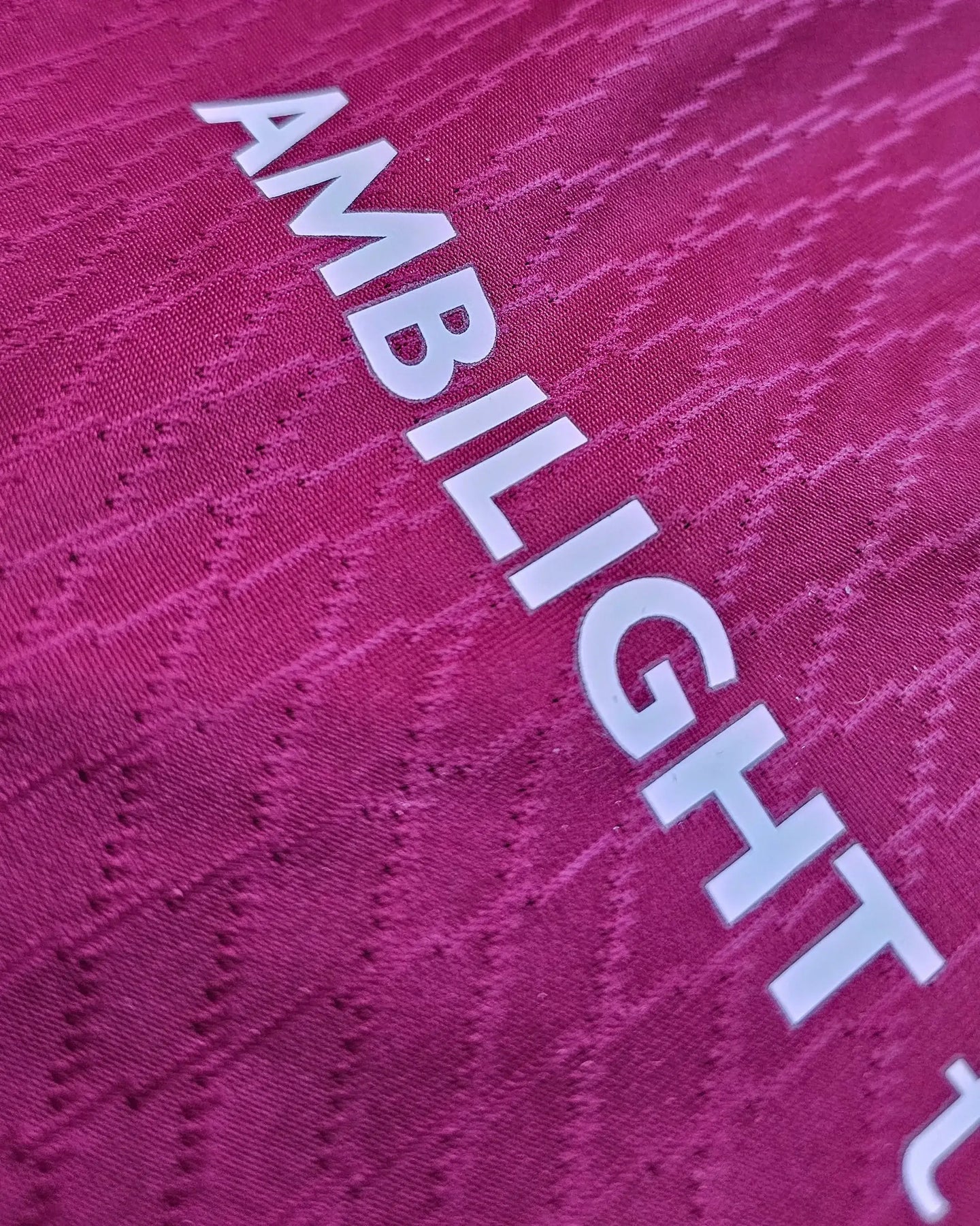 Close-up showing the 'AMBILIGHT' branding in white on a pink football shirt fabric.